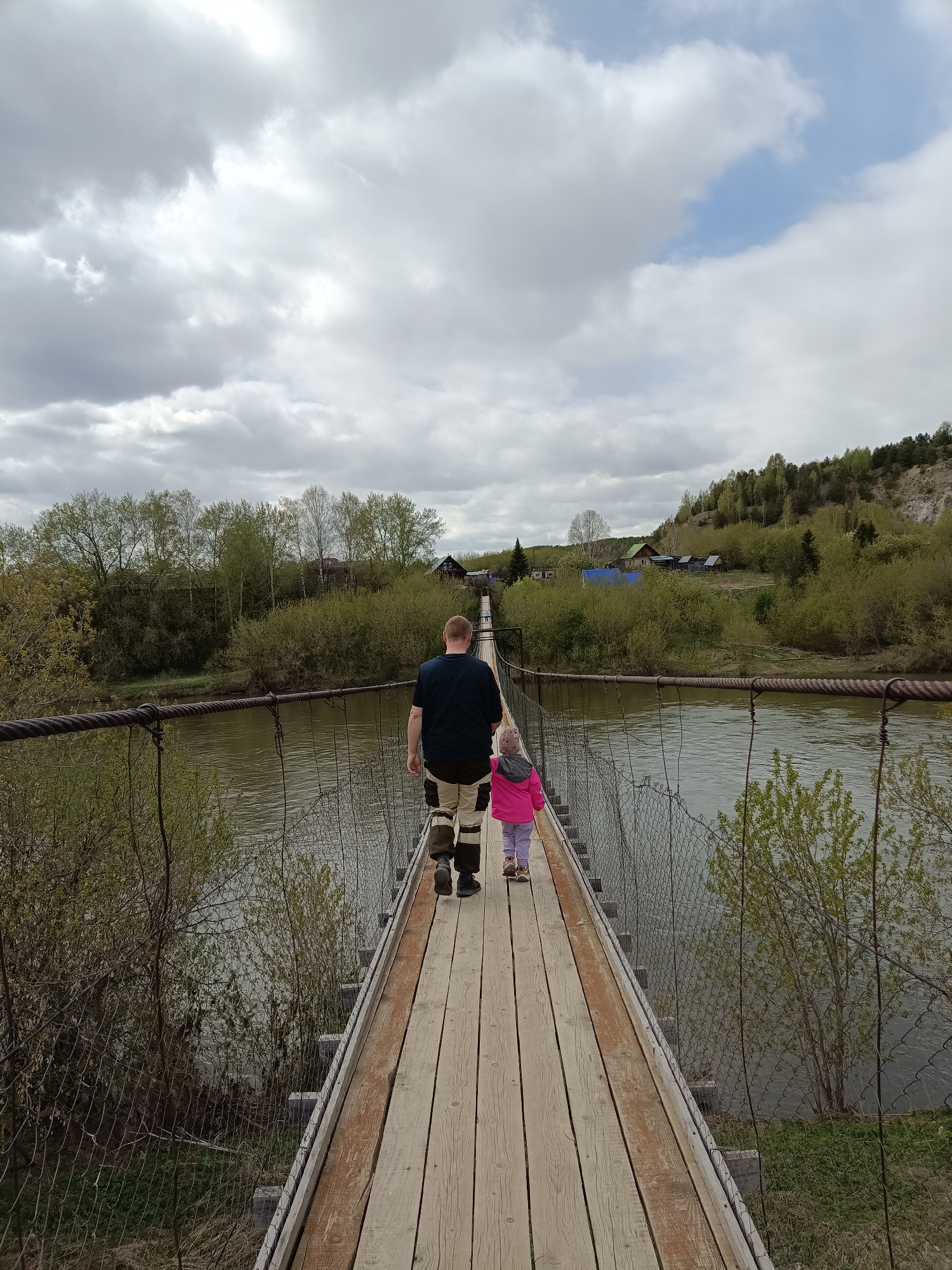Adult and child cross wooden bridge in Russian town