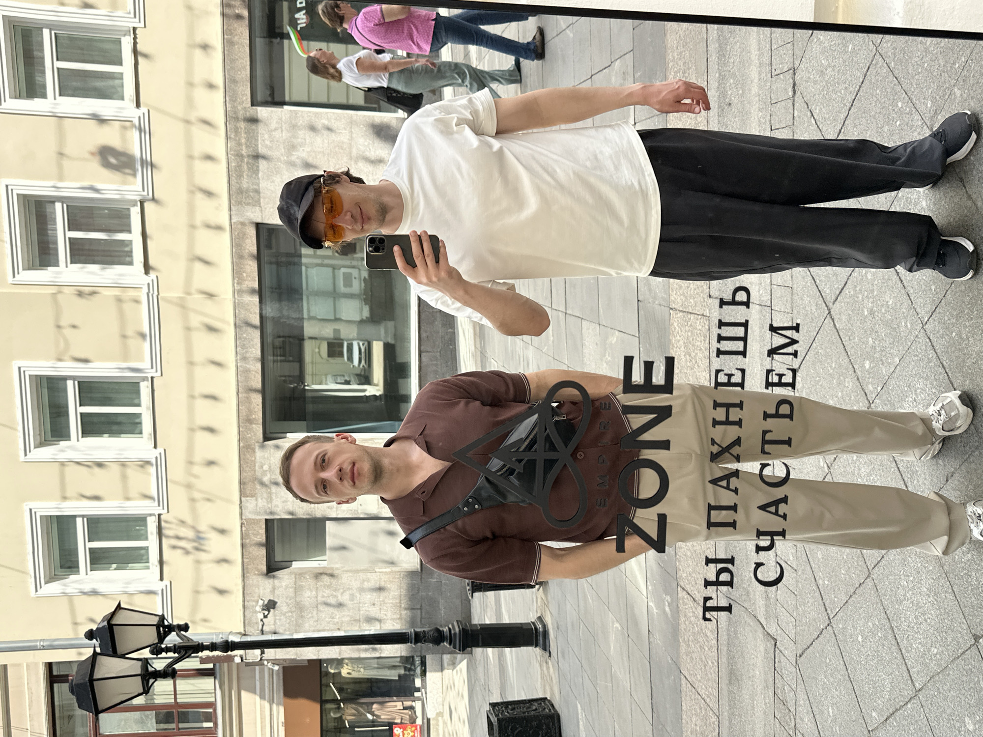 Two men take selfies at Moscow storefront mirror