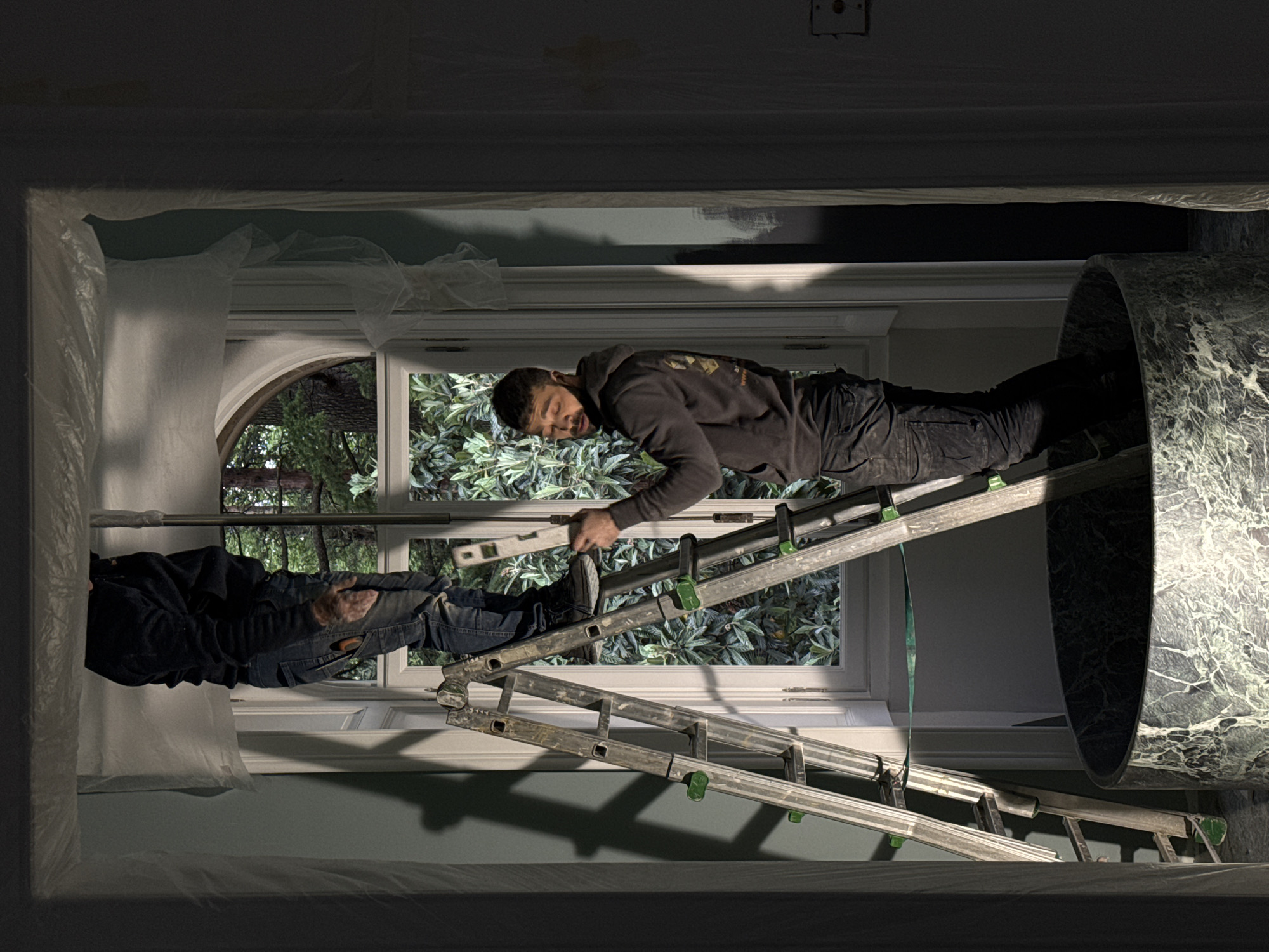 Two workers on ladder during renovations in Erba