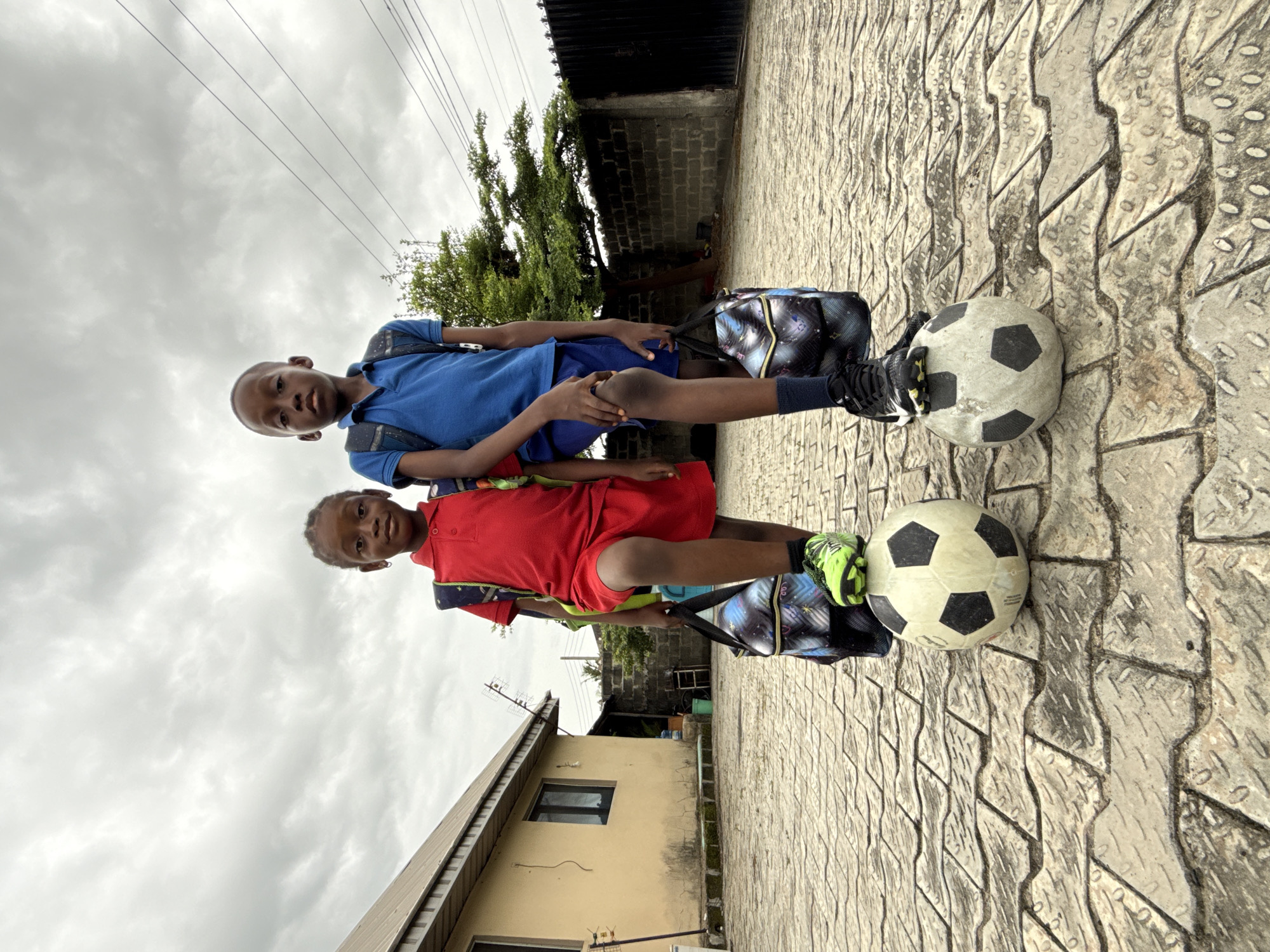 Two boys with soccer balls spotted on pavement in Ado