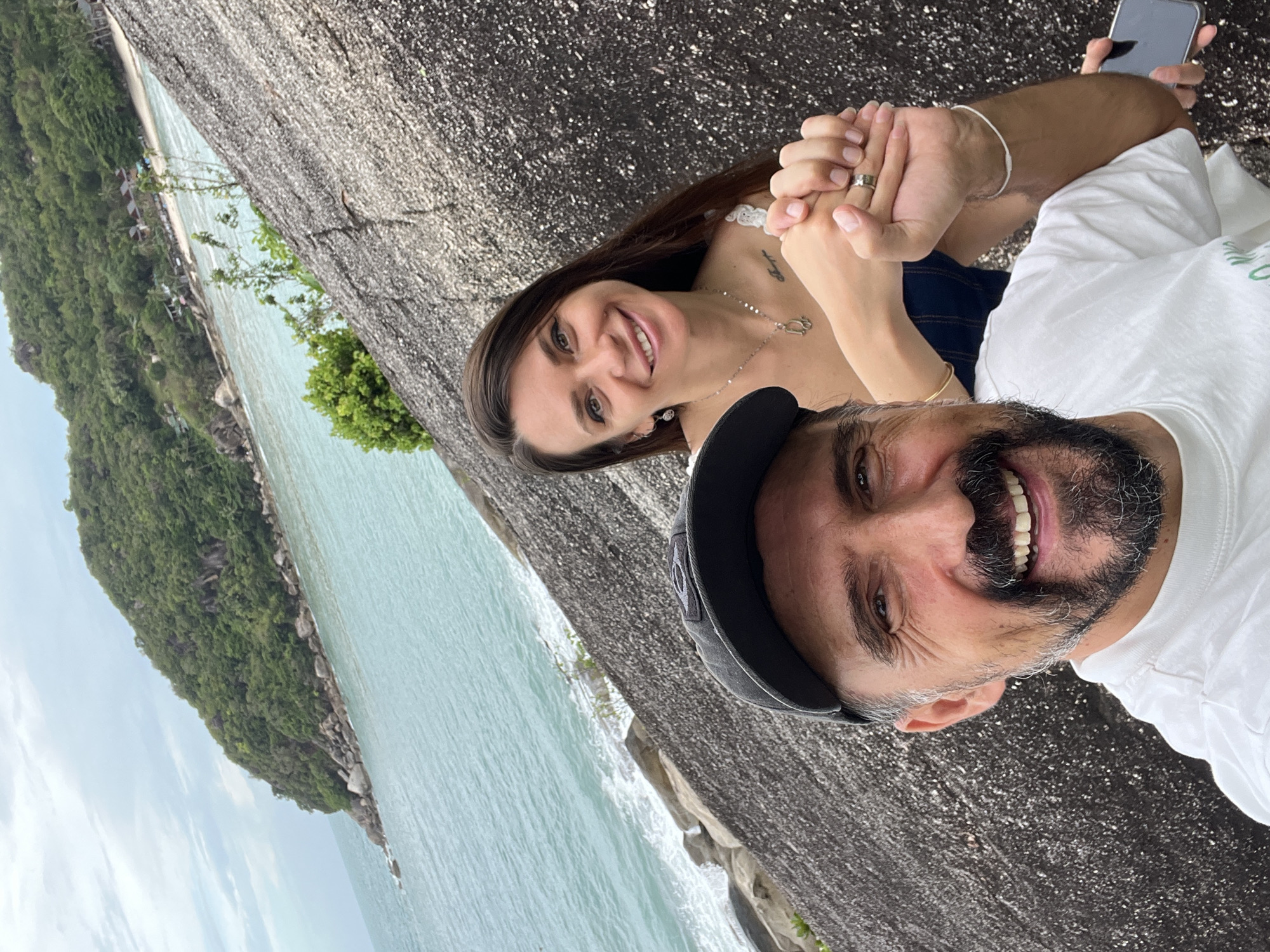 Tourists photograph scenic bay while local works in Thai village