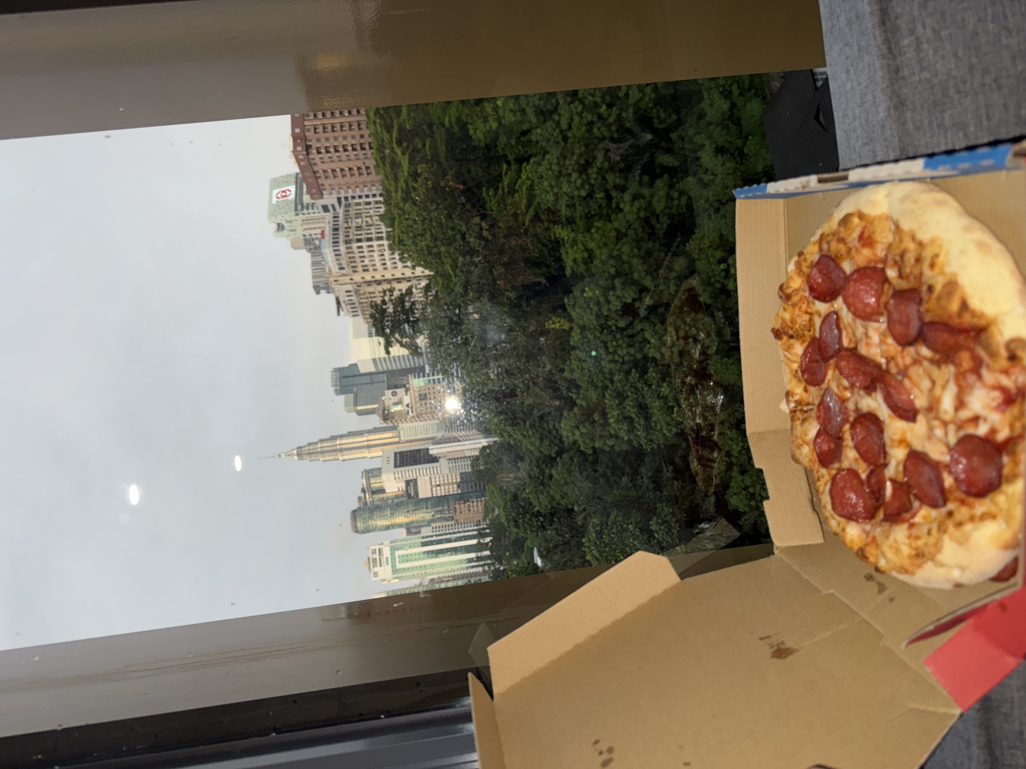 Pizza lunch documented overlooking Kuala Lumpur skyline