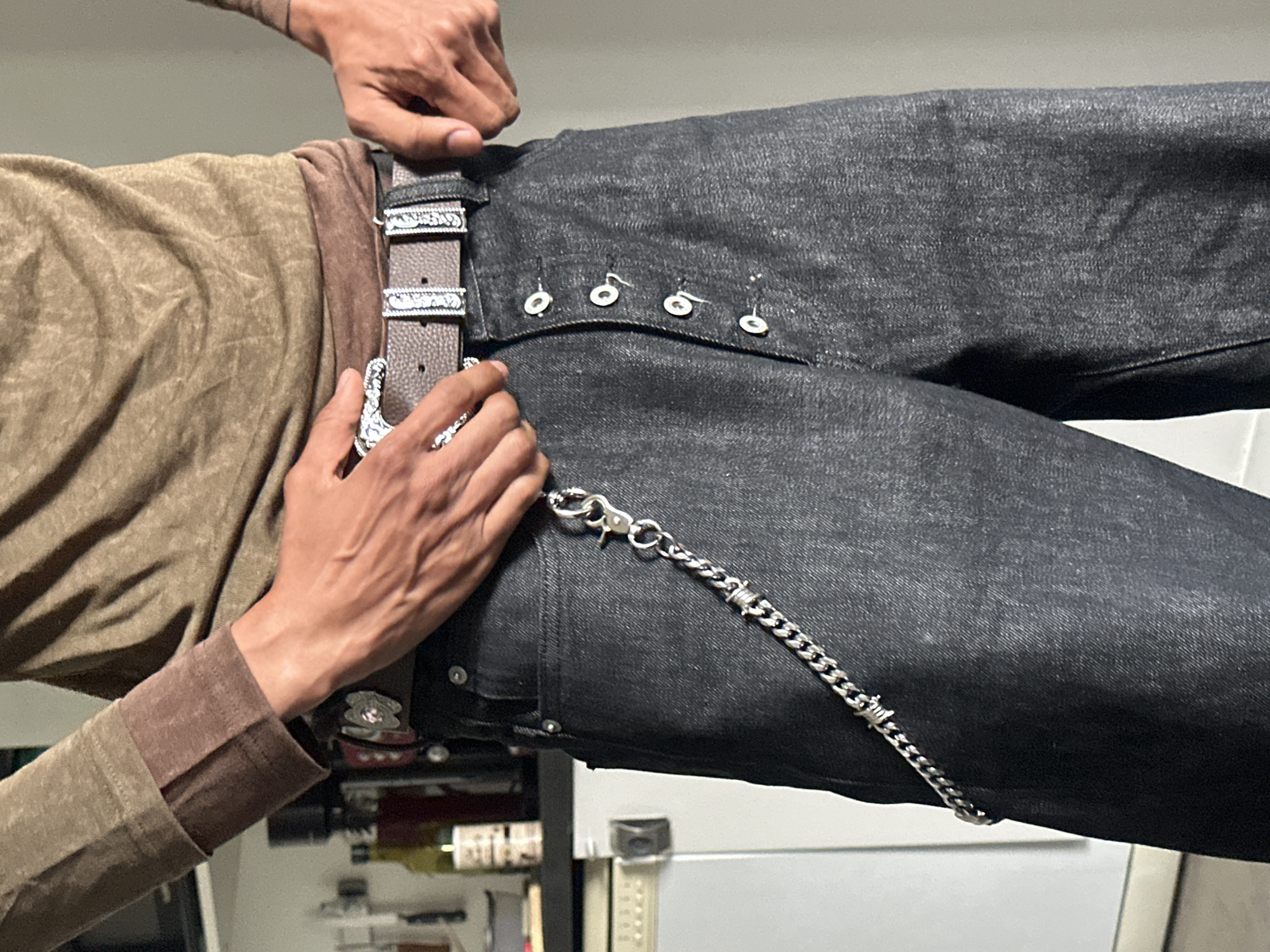 Man adjusts ornate belt on jeans in Paris