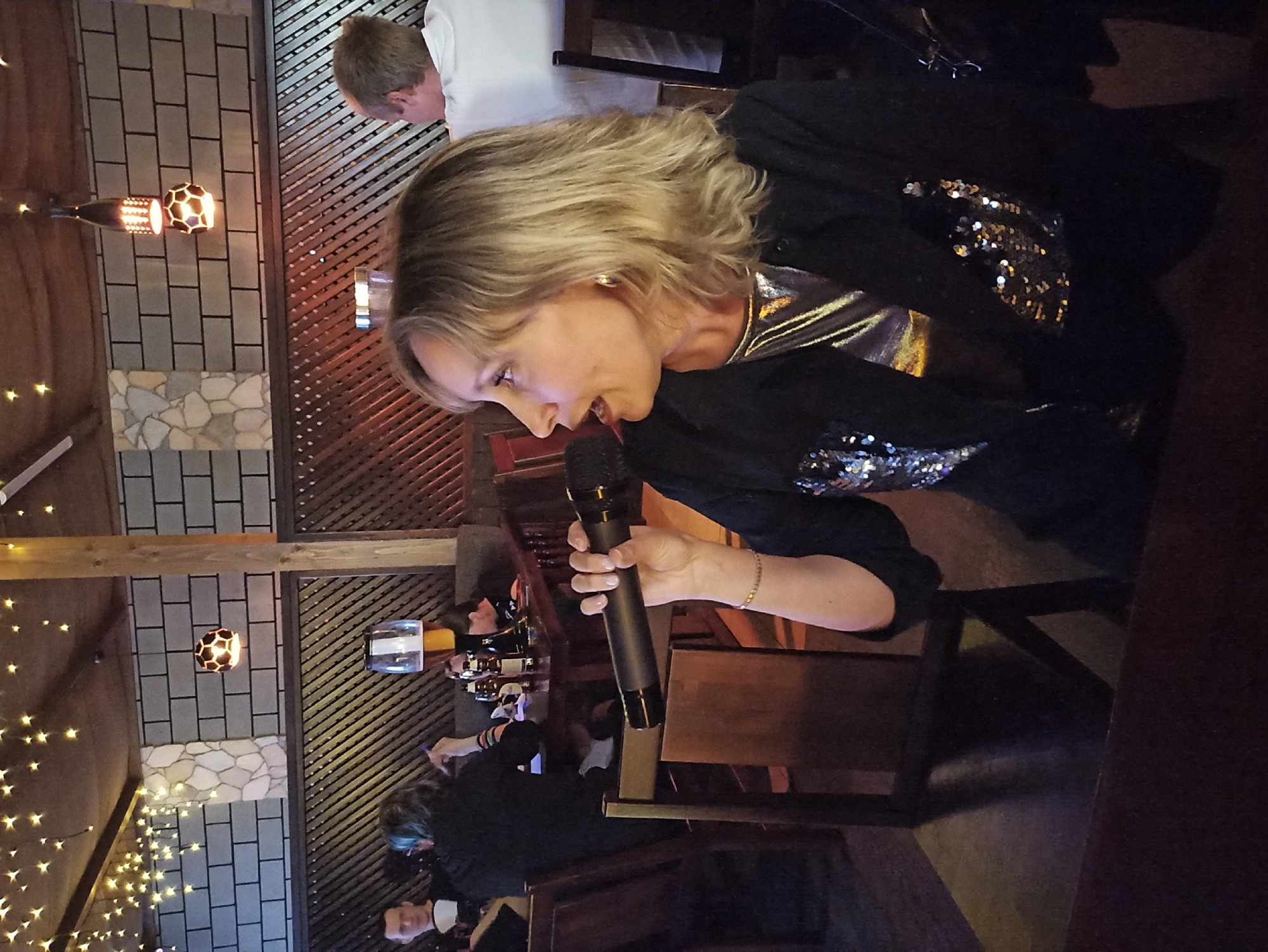 Karaoke performers entertain patrons at dimly lit restaurant bar