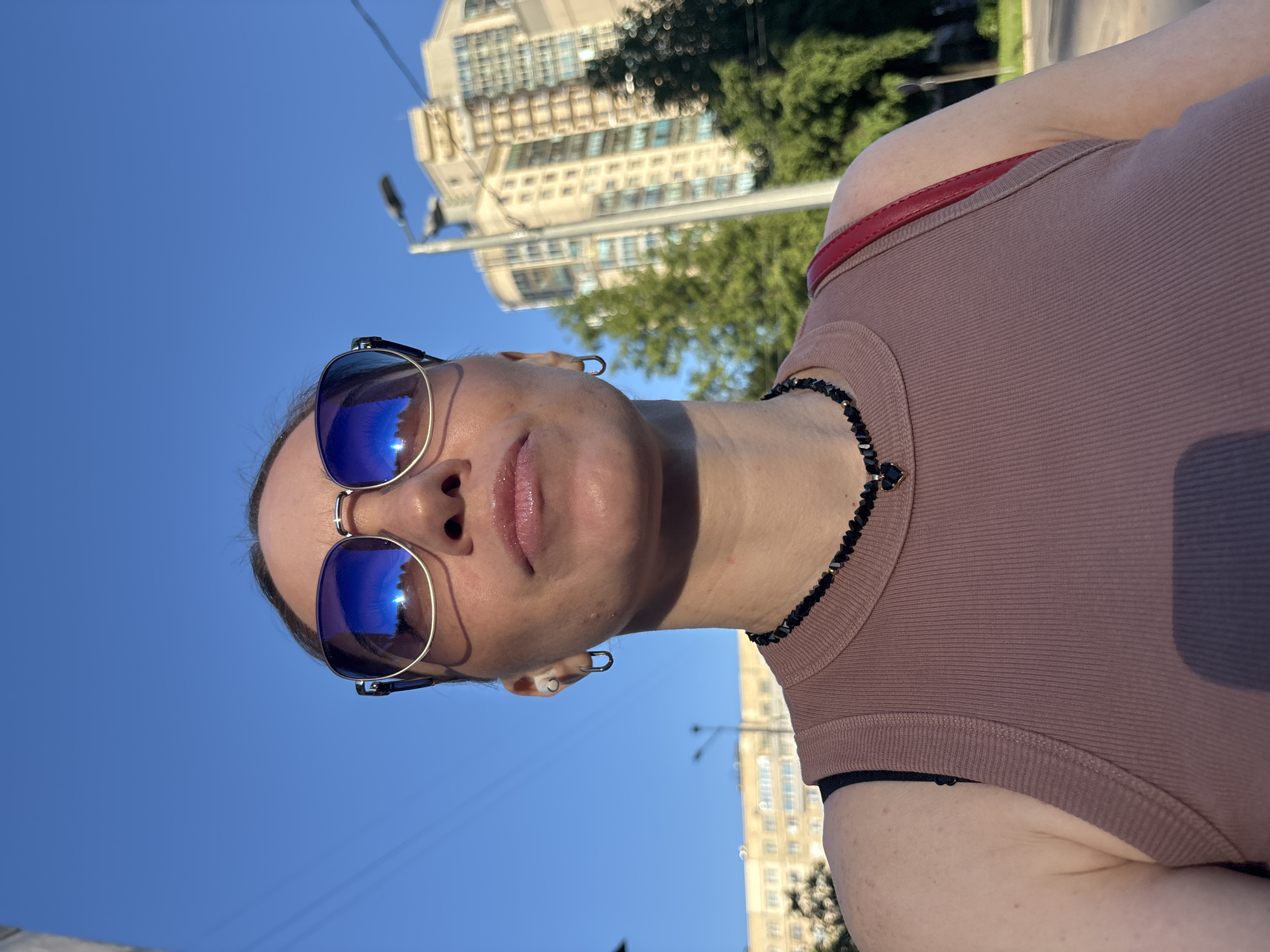 Woman photographed outdoors in Sinyavino wearing blue sunglasses