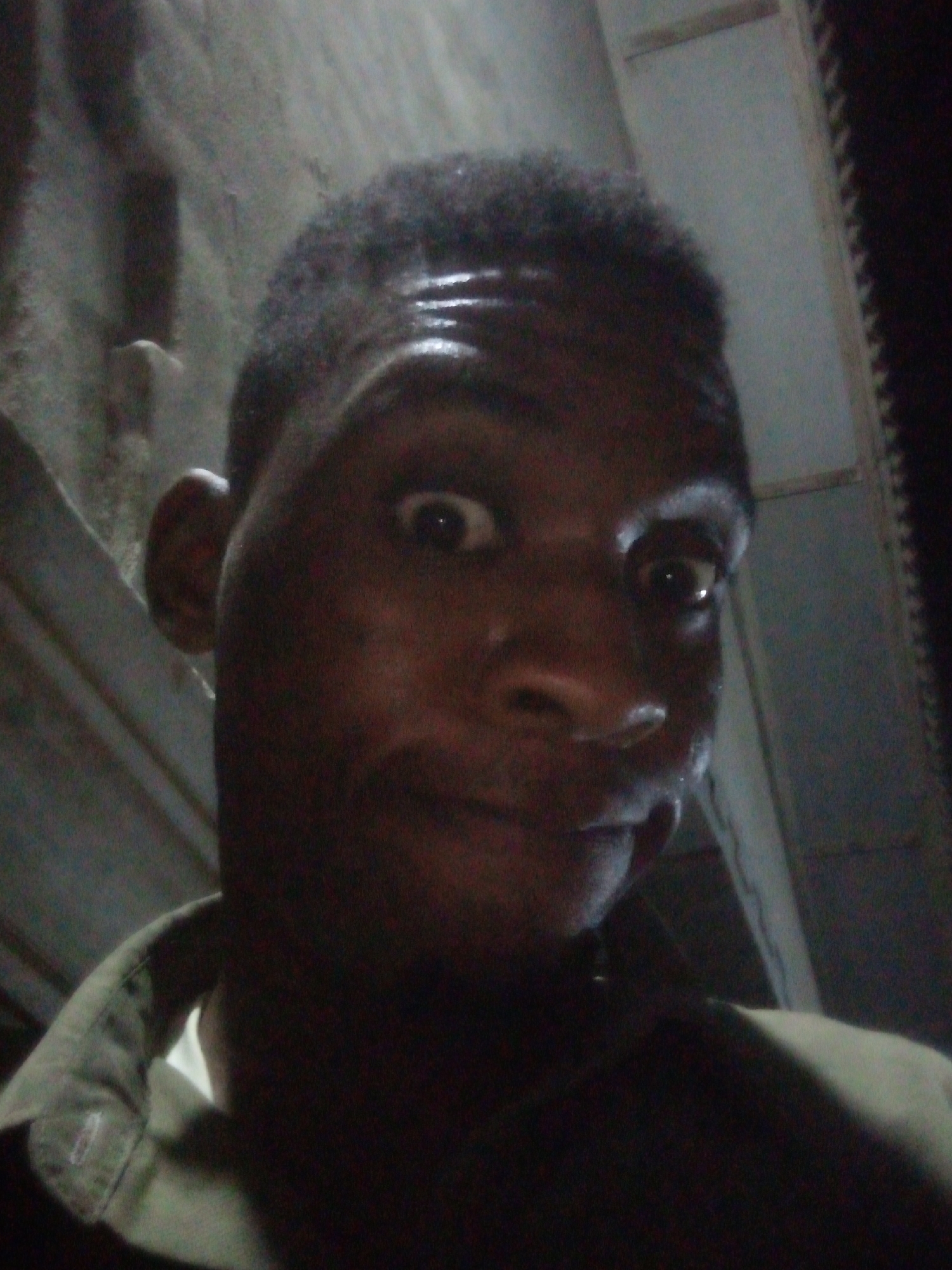 Man captures surprised selfie in poorly lit indoor location