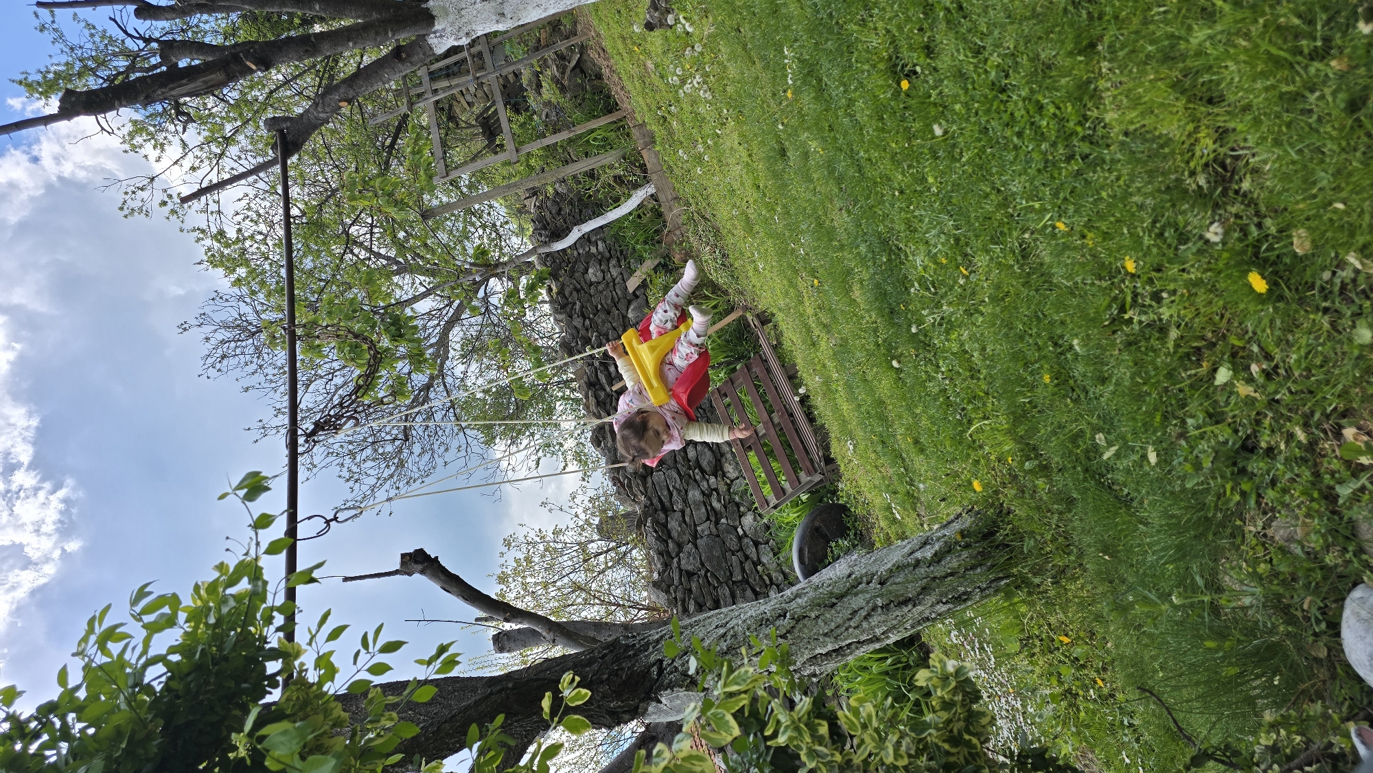 Toddler plays on swing in Bulgarian garden