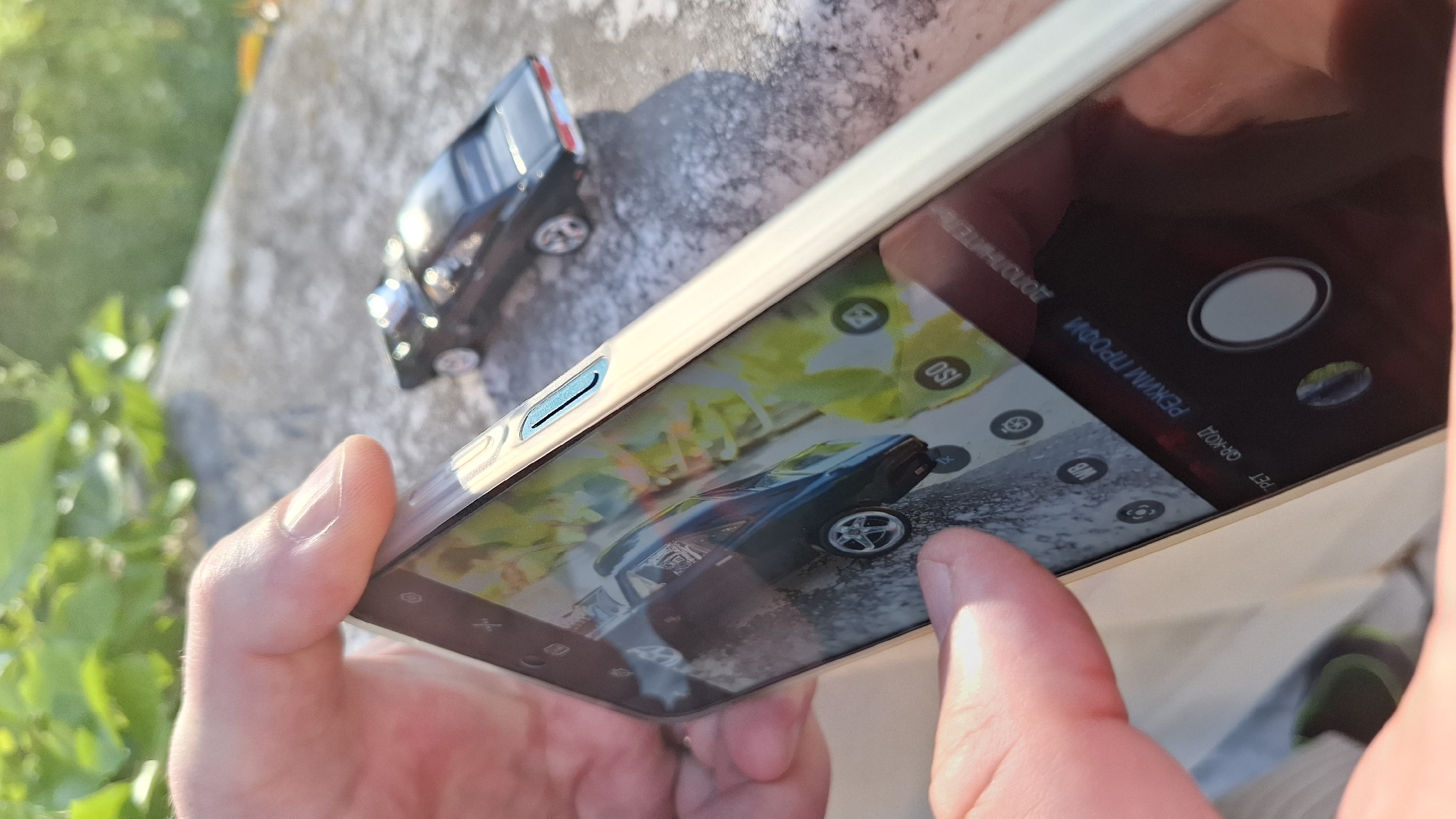 Person photographs black toy car with smartphone