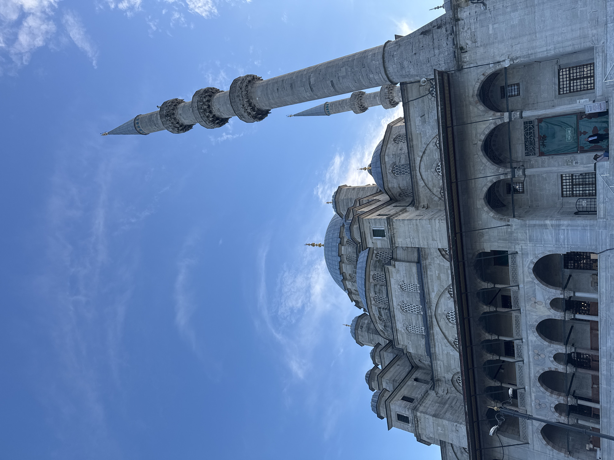 Tourist photographs historic Yeni Cami mosque in Istanbul