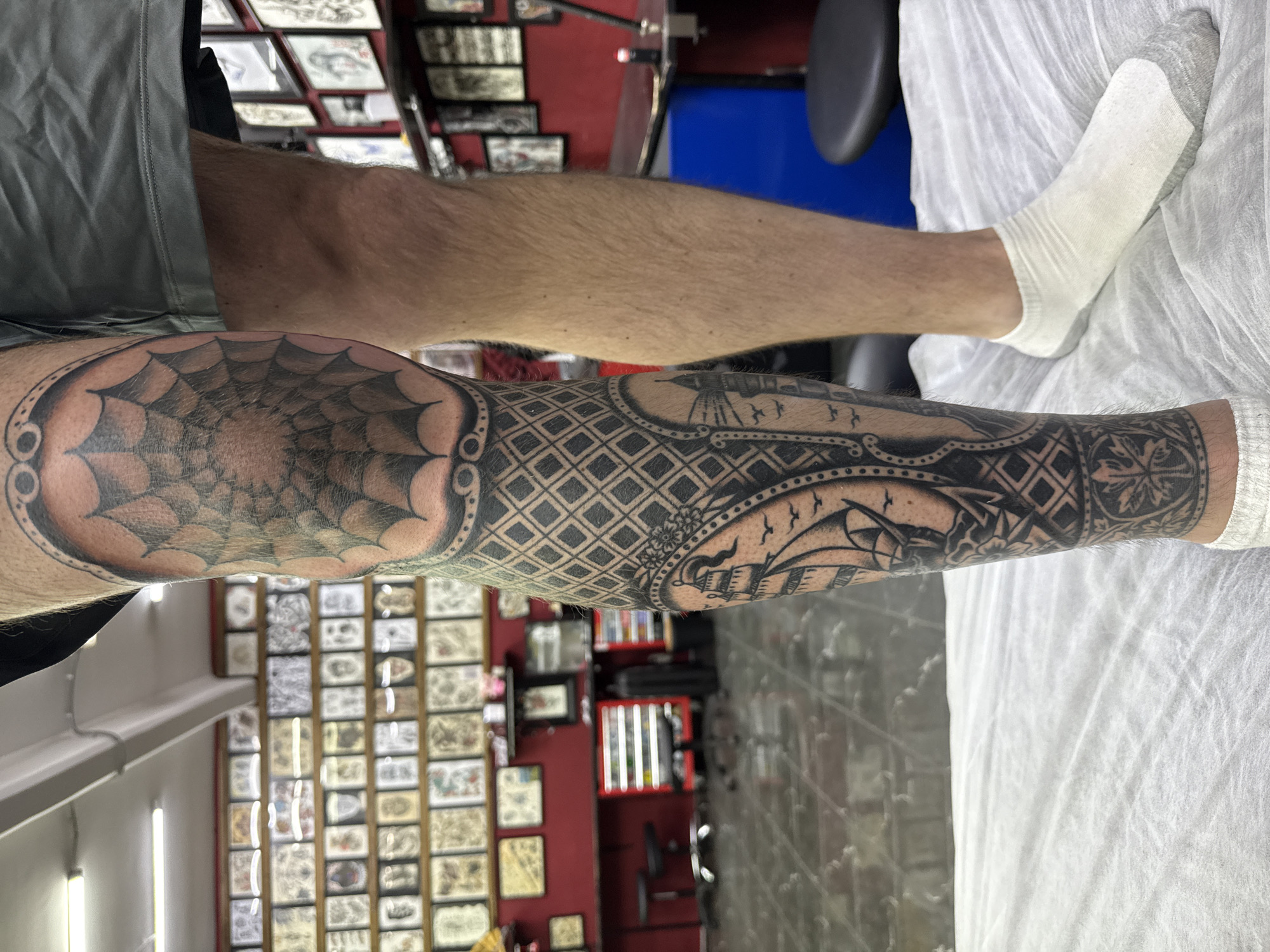 Elaborate leg tattoo with spiderweb and sailboat designs observed in Moscow