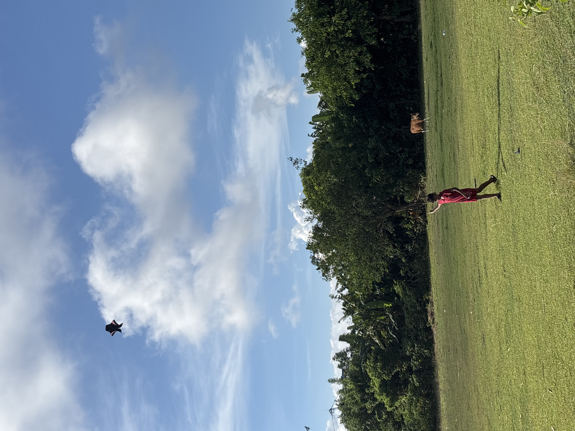 Person in red stands in sunny field in Kuta Selatan