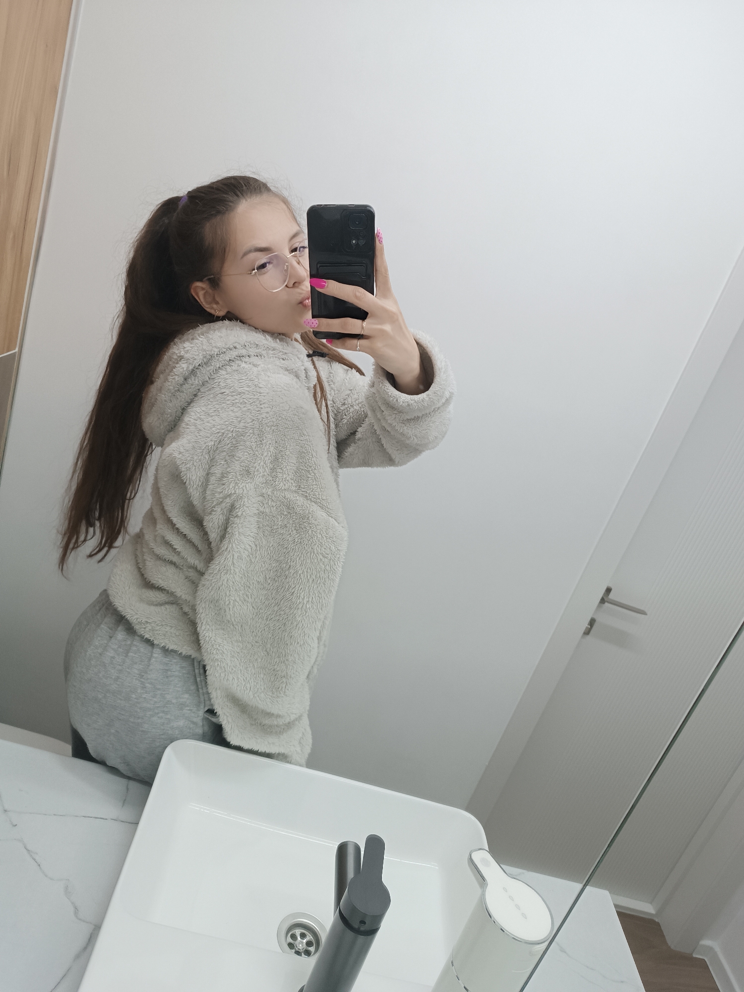 Woman takes bathroom selfie in gray outfit