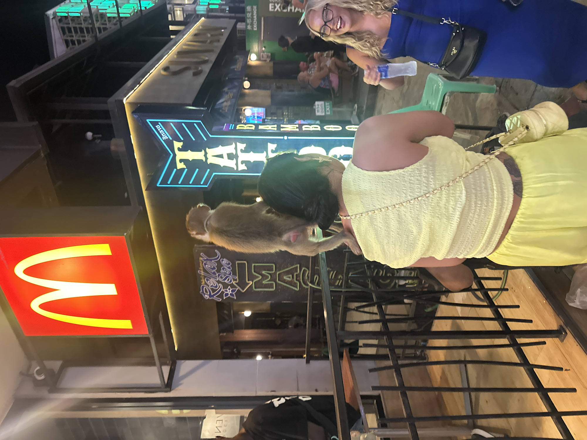 Monkey sits on woman's shoulder near McDonald's in Thailand