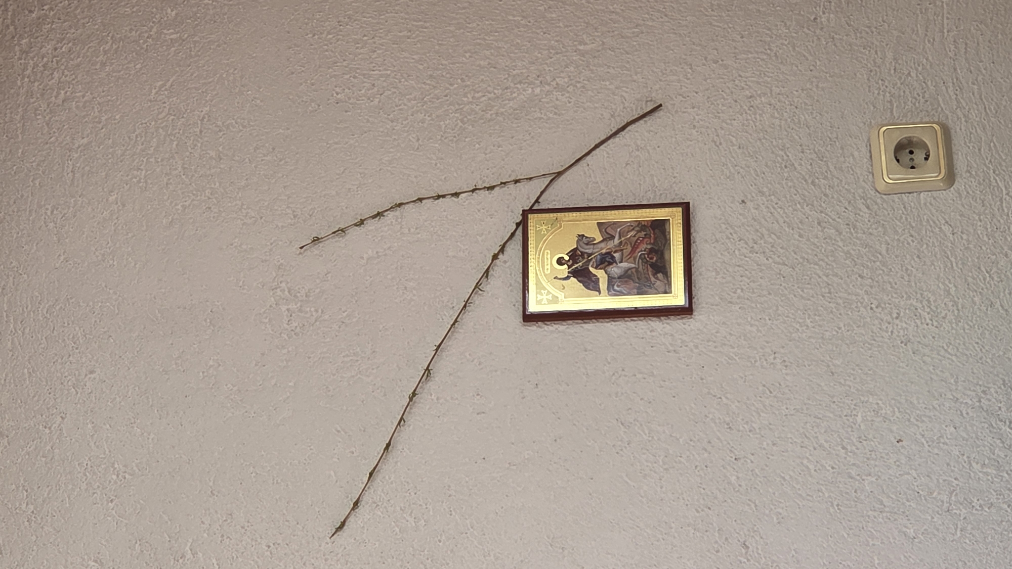 Religious icon displayed on textured wall with mounted items