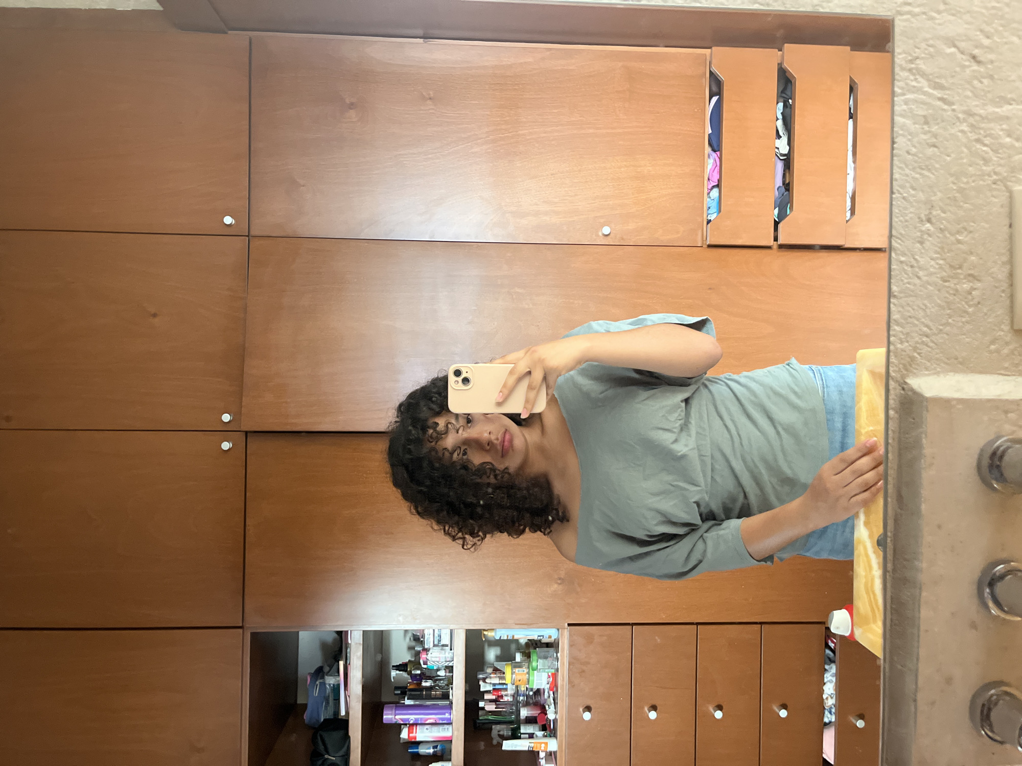 Person takes mirror selfie near open wooden cabinet