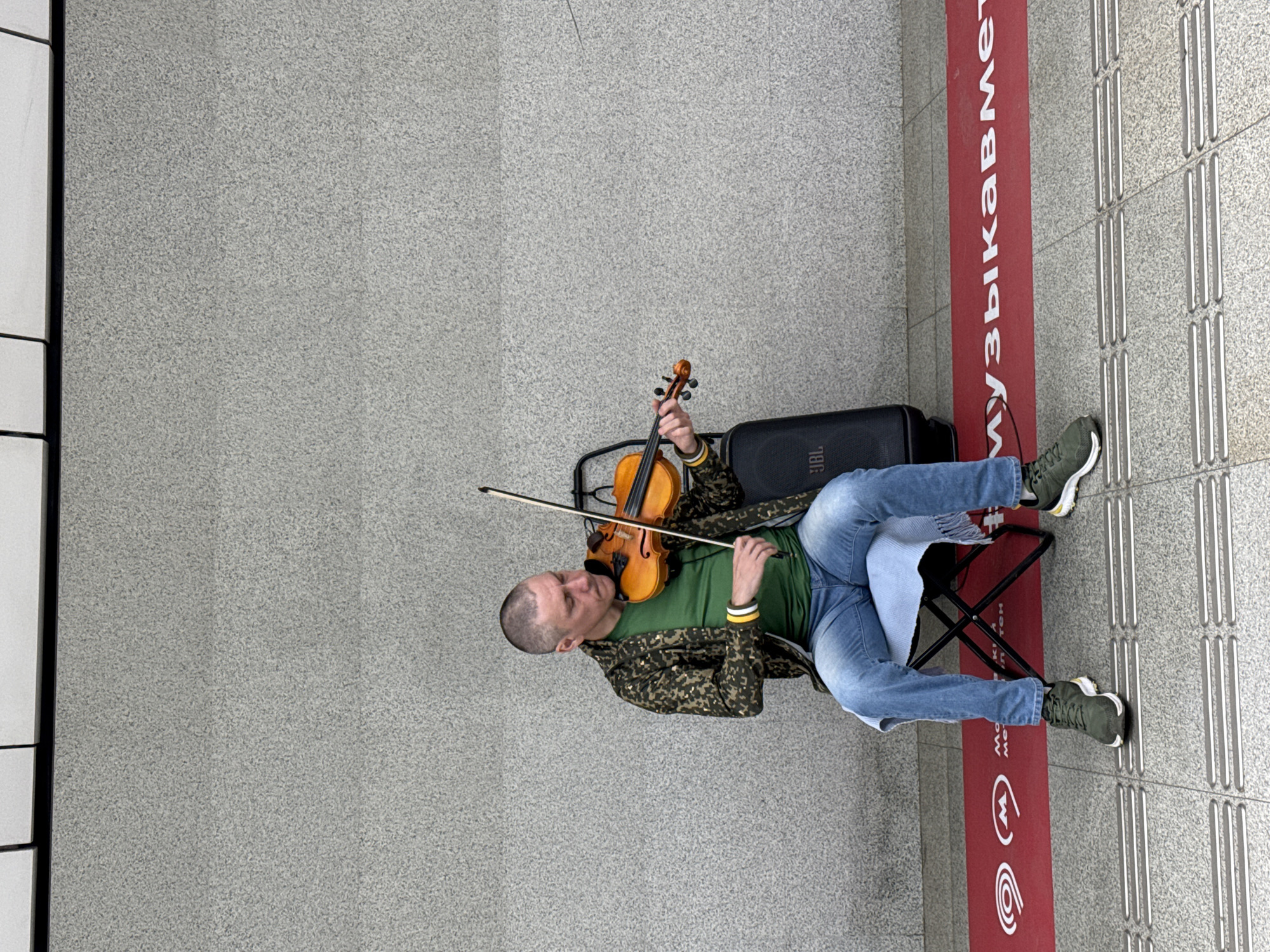 Street violinist performs in Moscow; photo album reviewed nearby