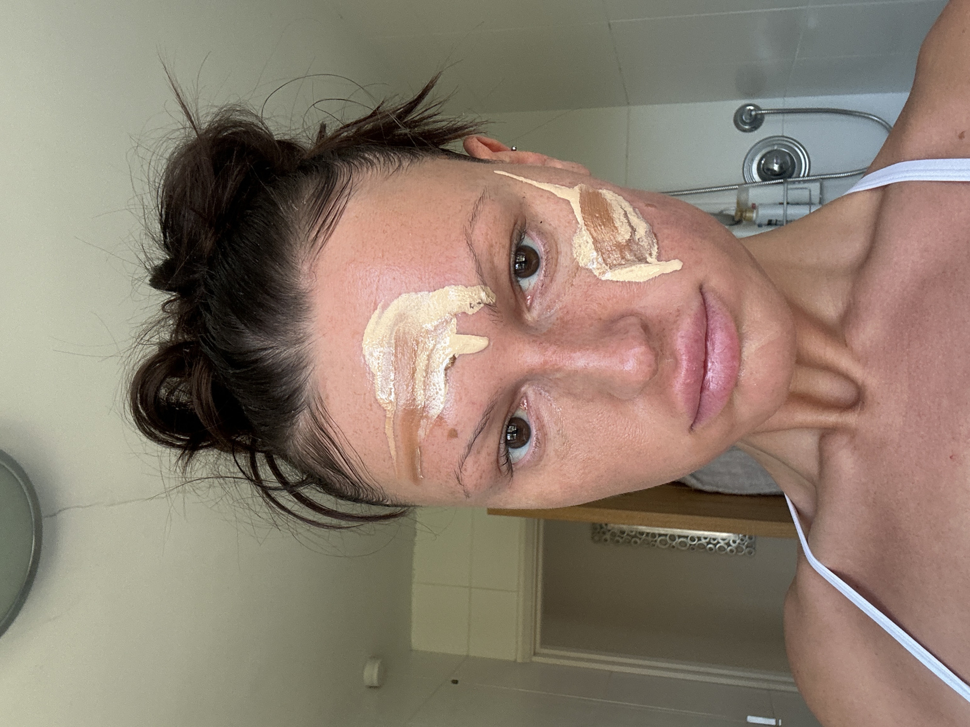 Woman applies makeup in bathroom, Wealden UK morning routine