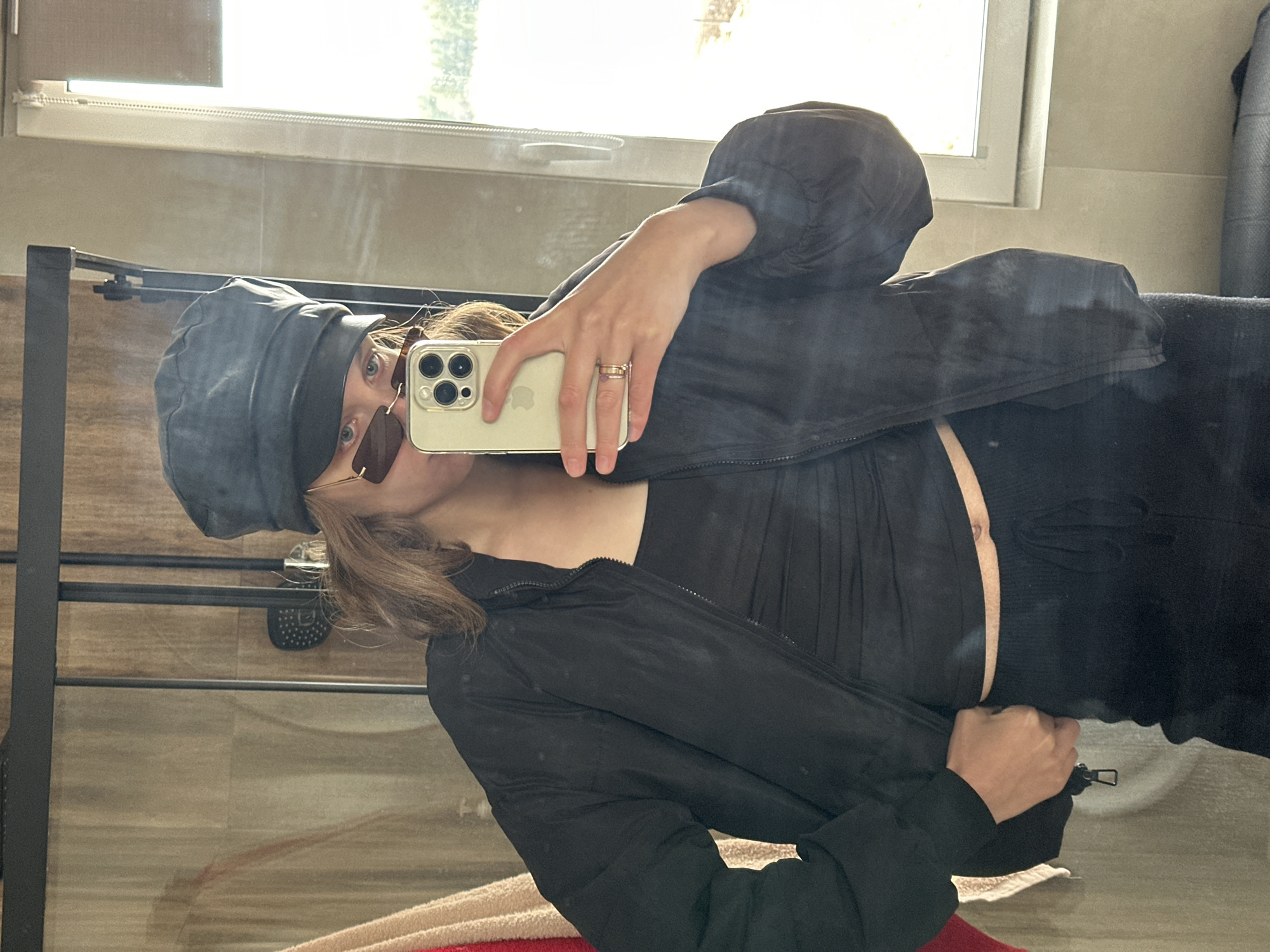 Person takes bathroom selfie with gold iPhone wearing black outfit