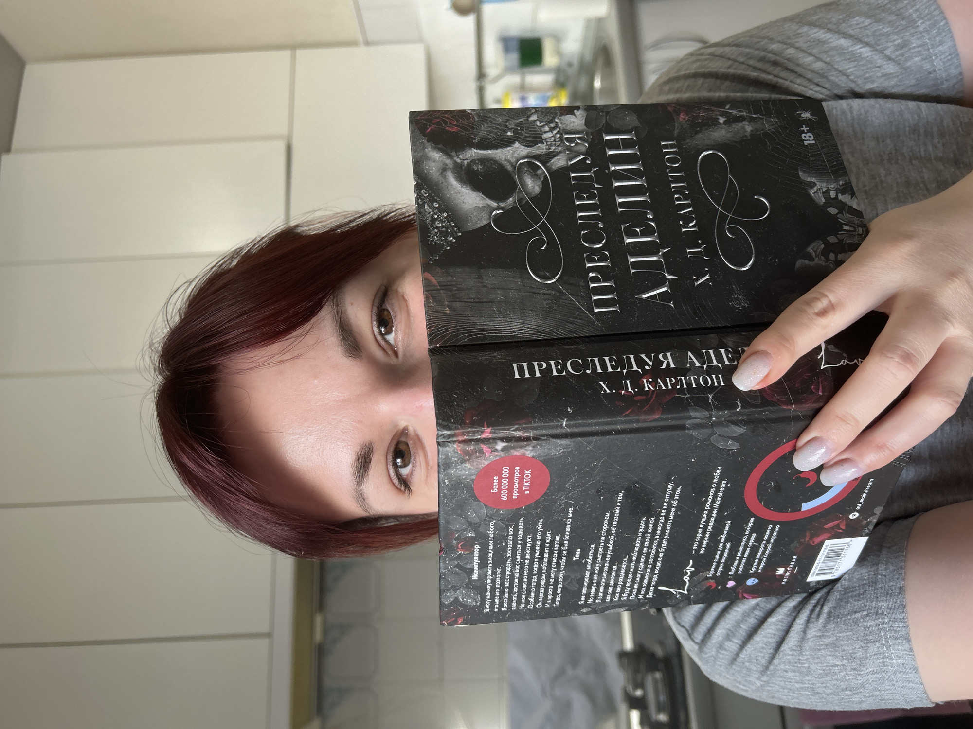 Woman reads gothic novel while eating and drinking in kitchen