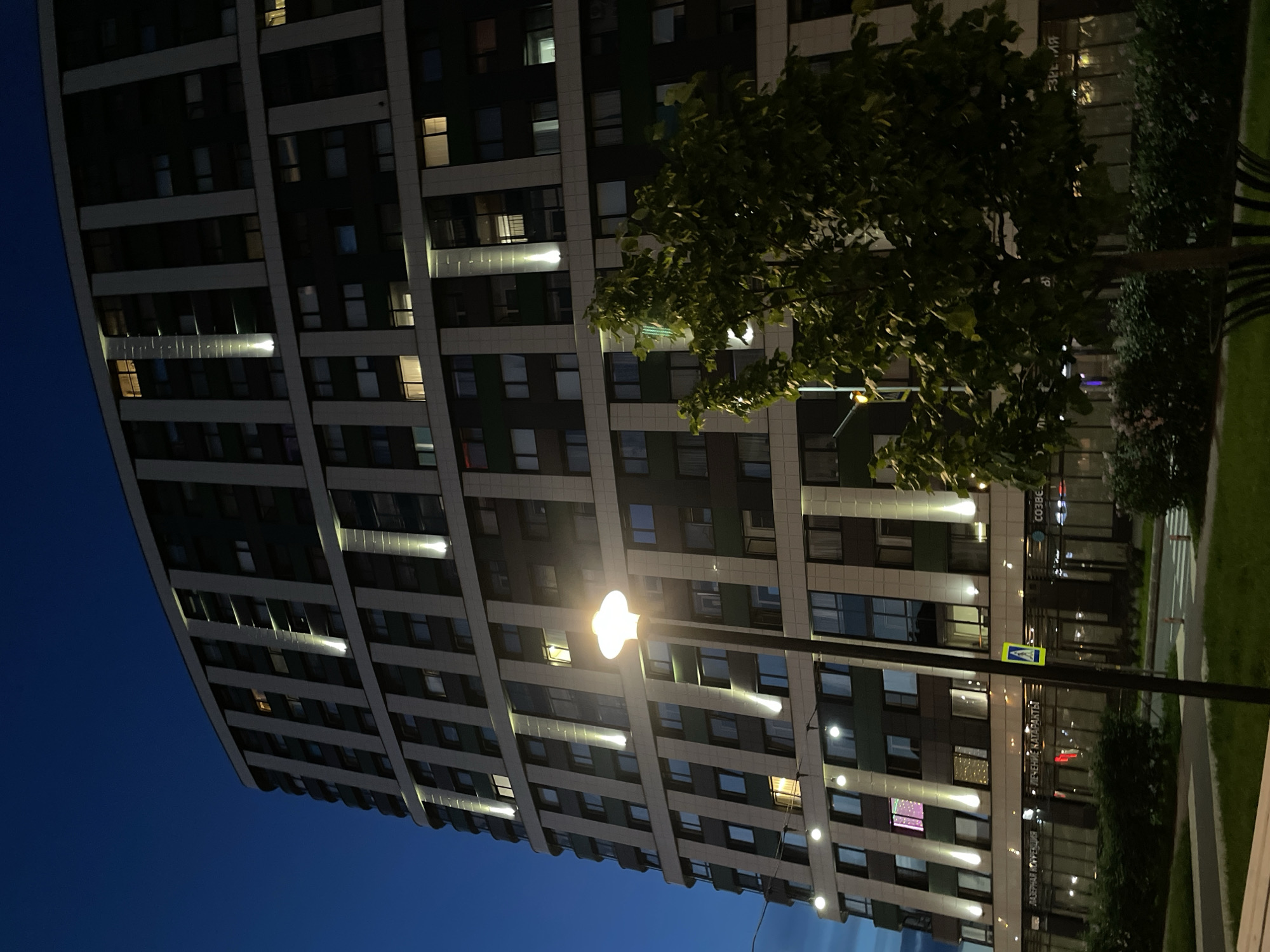 Modern high-rise building illuminated at dusk with glowing windows