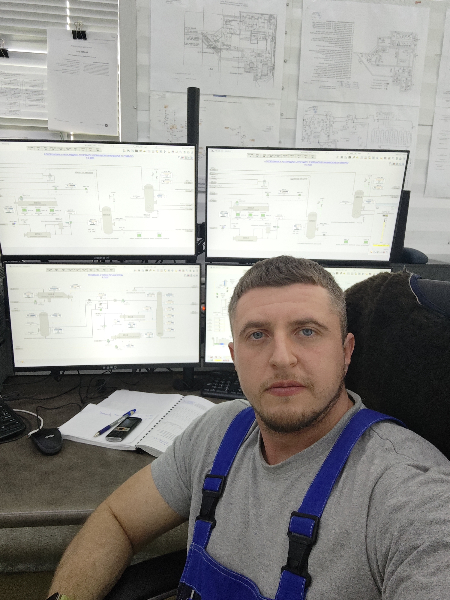 Worker monitors industrial processes from multi-screen control station