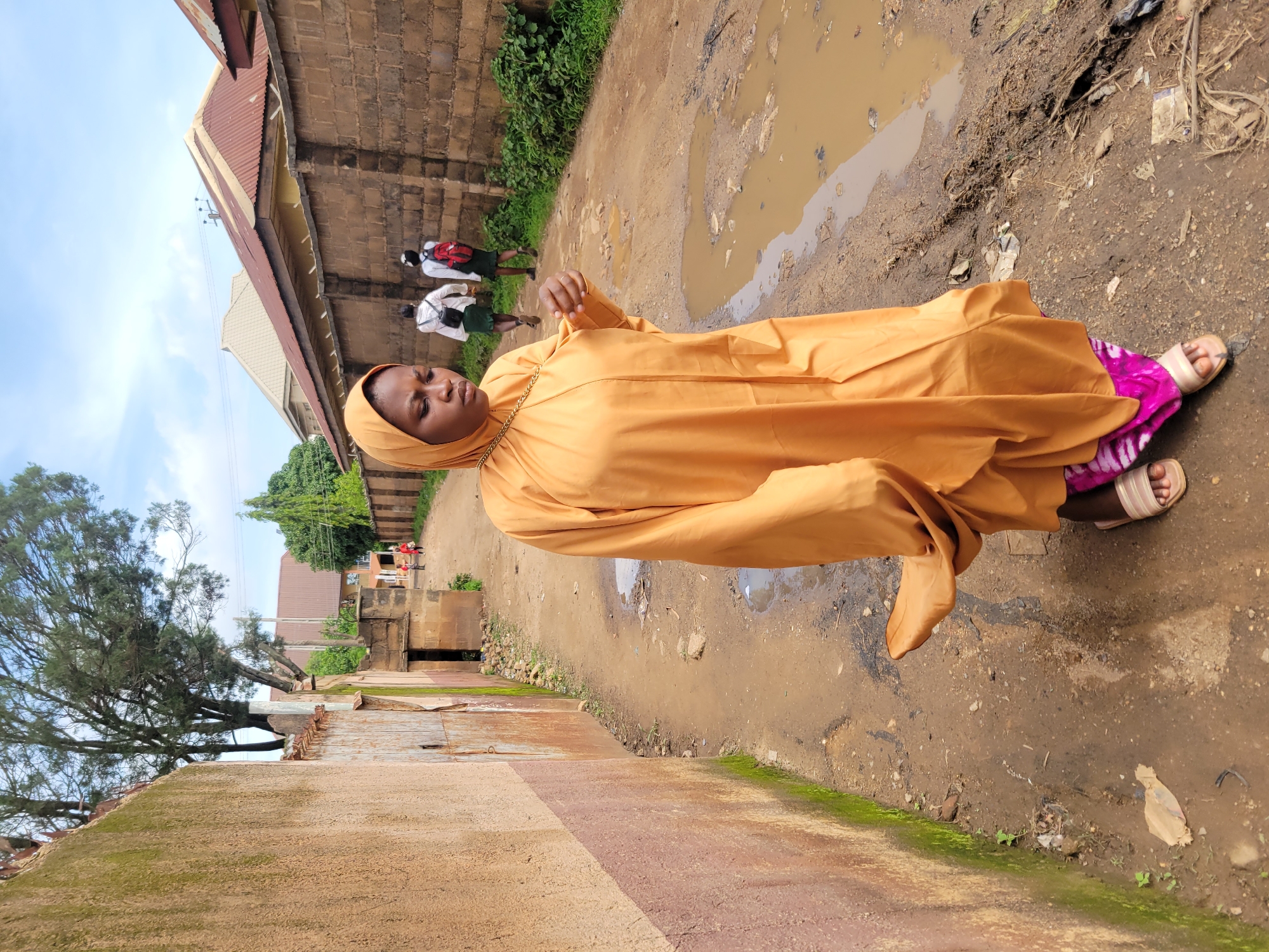 Everyday street life on a muddy Jos neighborhood road