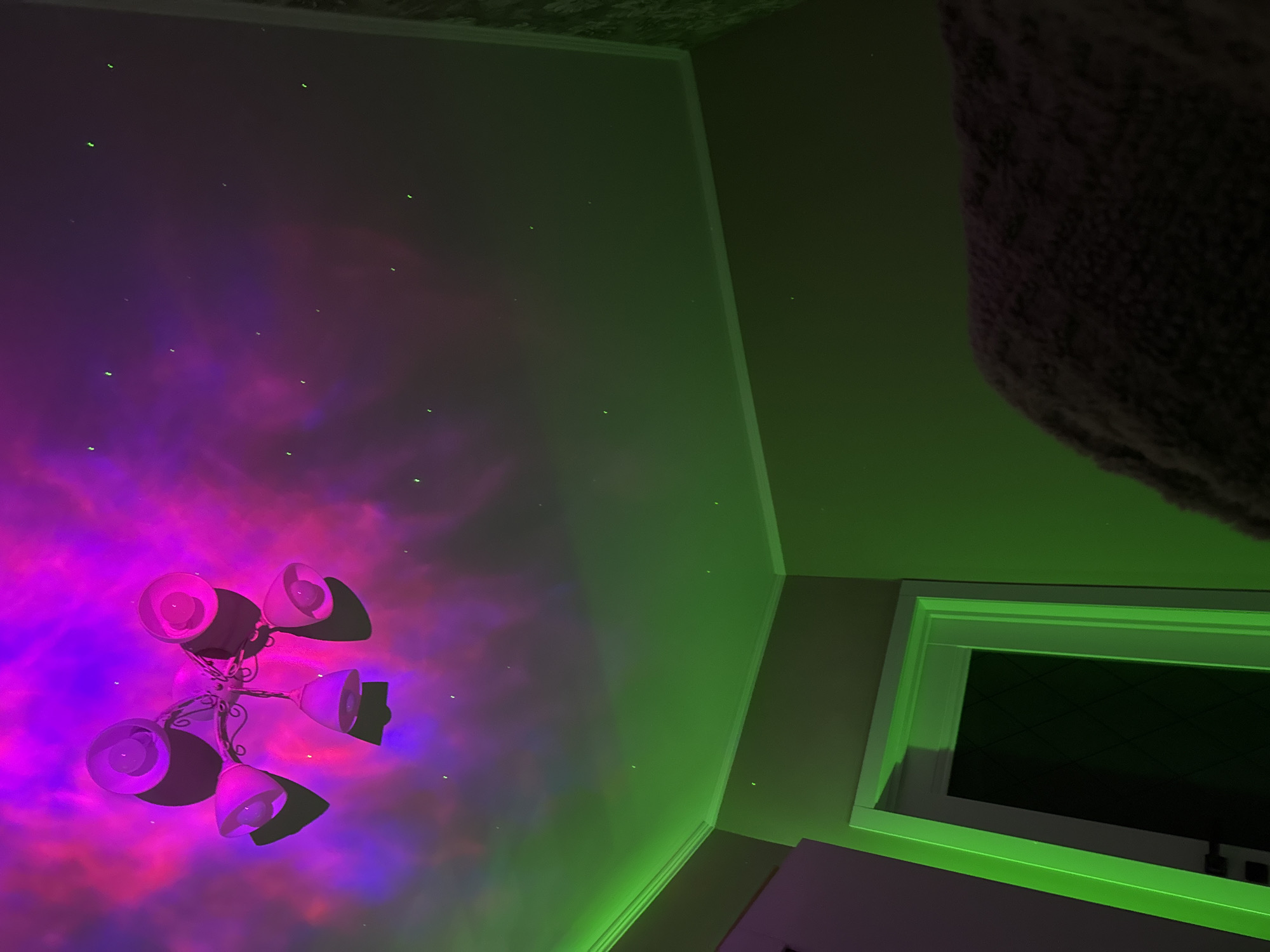 Room ceiling features cosmic nebula projection with chandelier centerpiece
