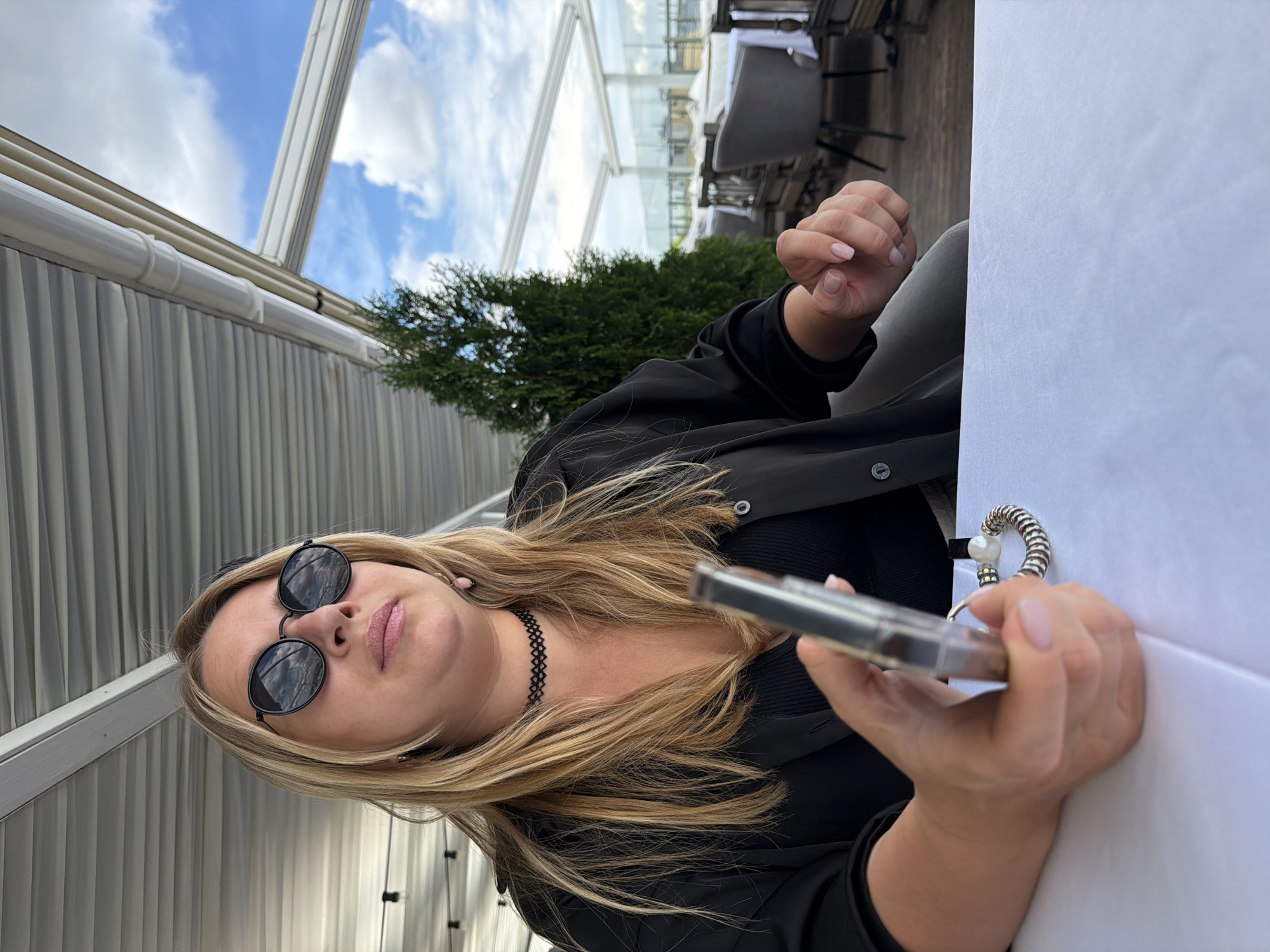 Relaxing at a rooftop terrace table, phone in hand.