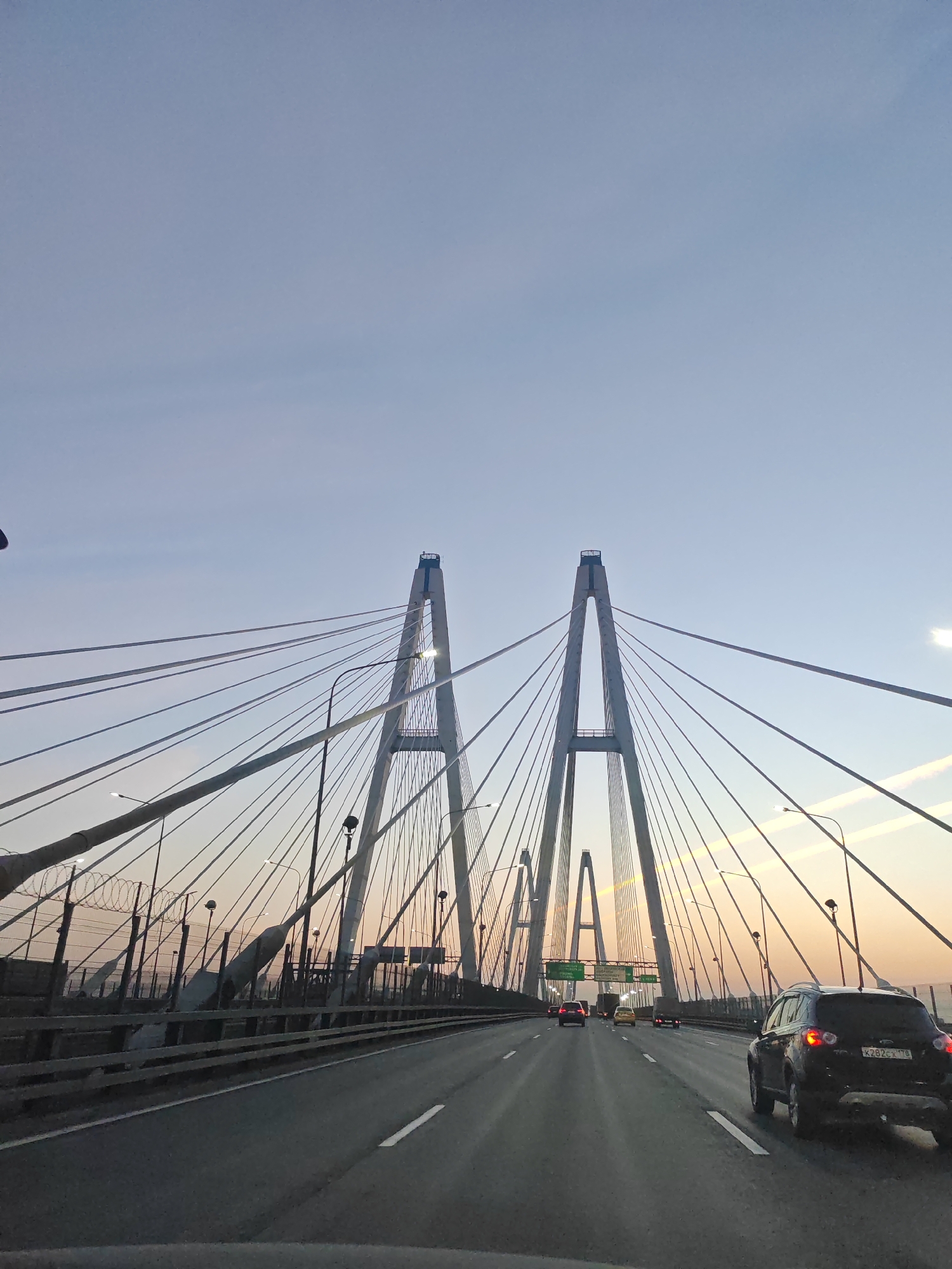 Traffic flows on highway approaching cable-stayed bridge in Novosaratovka
