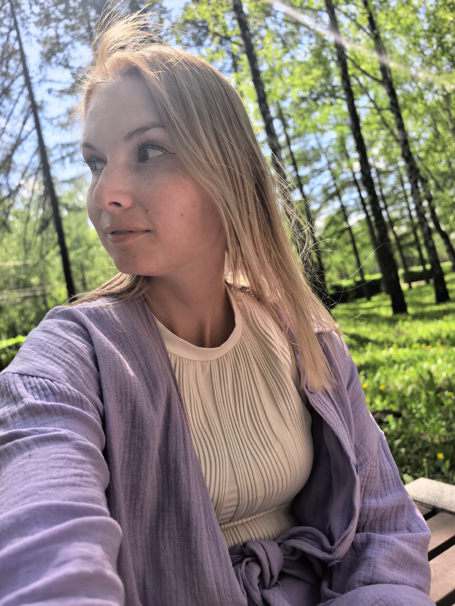 Woman reads book in Sterlitamak park amid birches