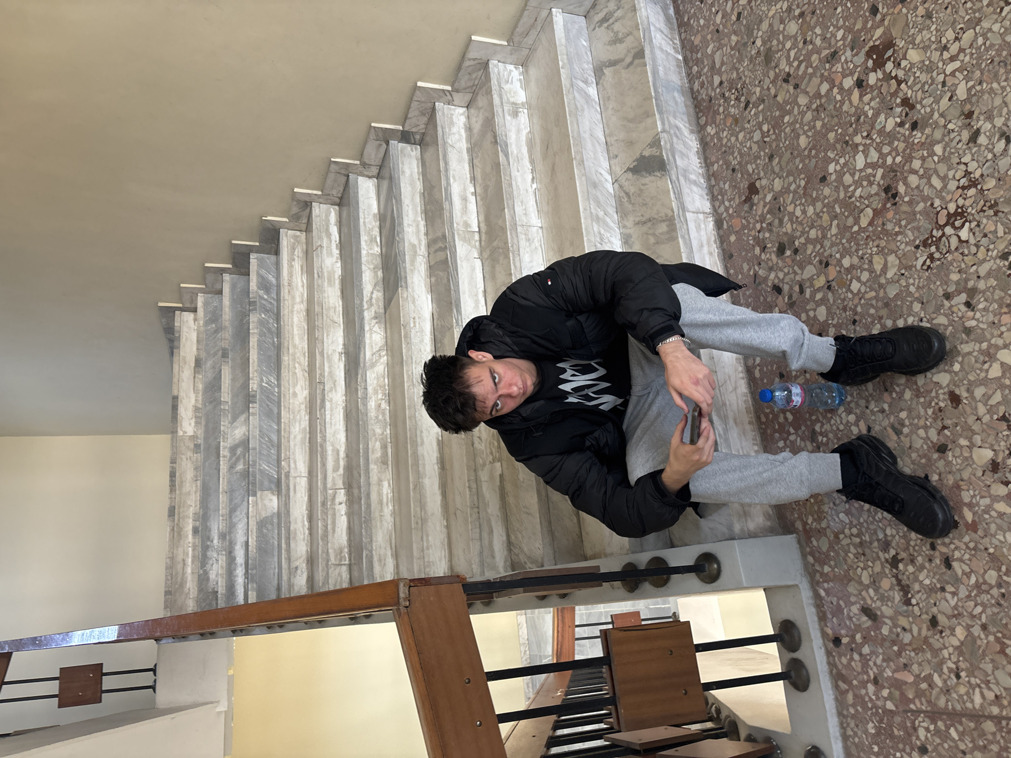 Young man sits on marble stairs in Plovdiv building