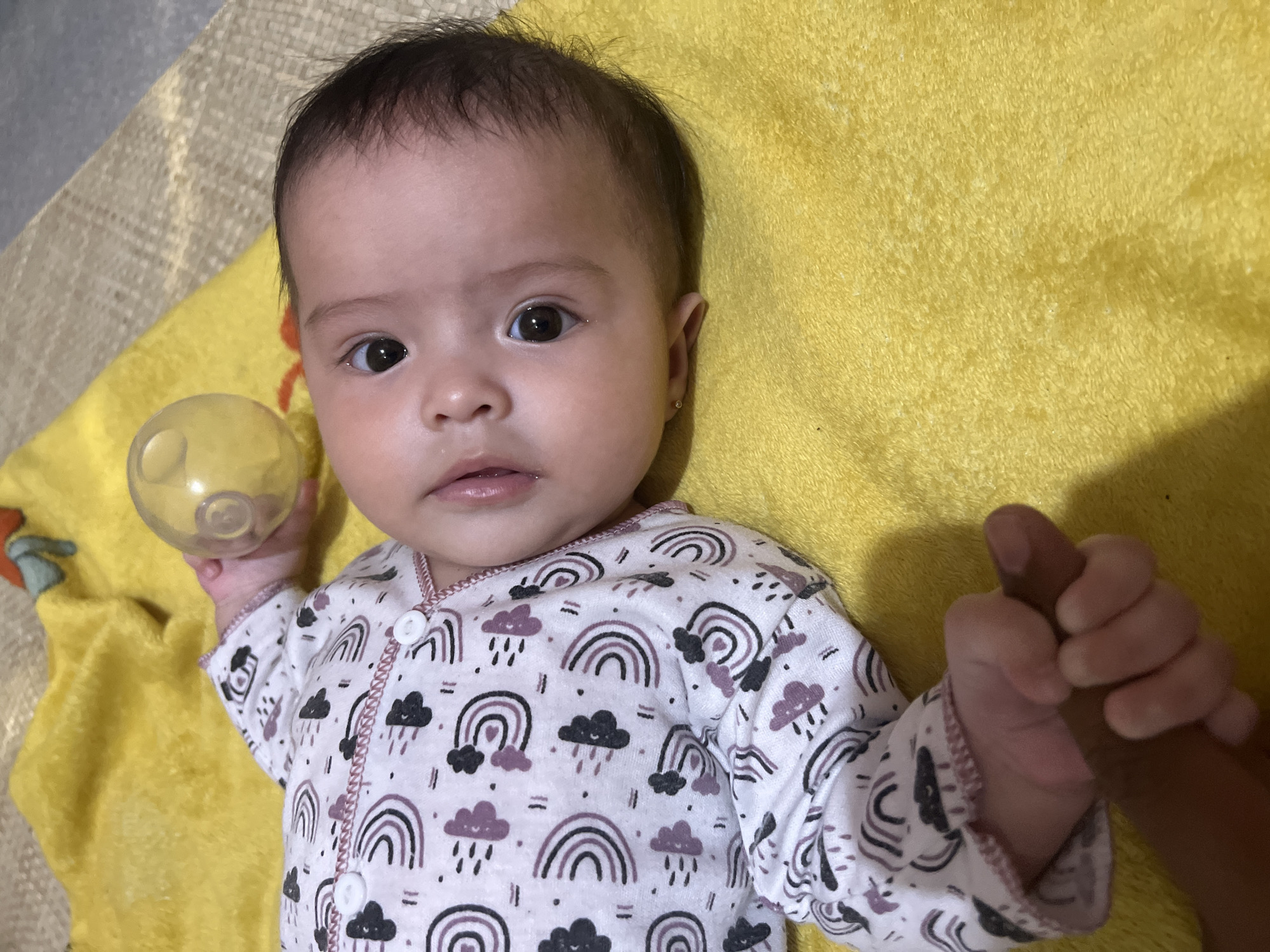 Baby on yellow blanket, rainbow onesie, Lhokseumawe