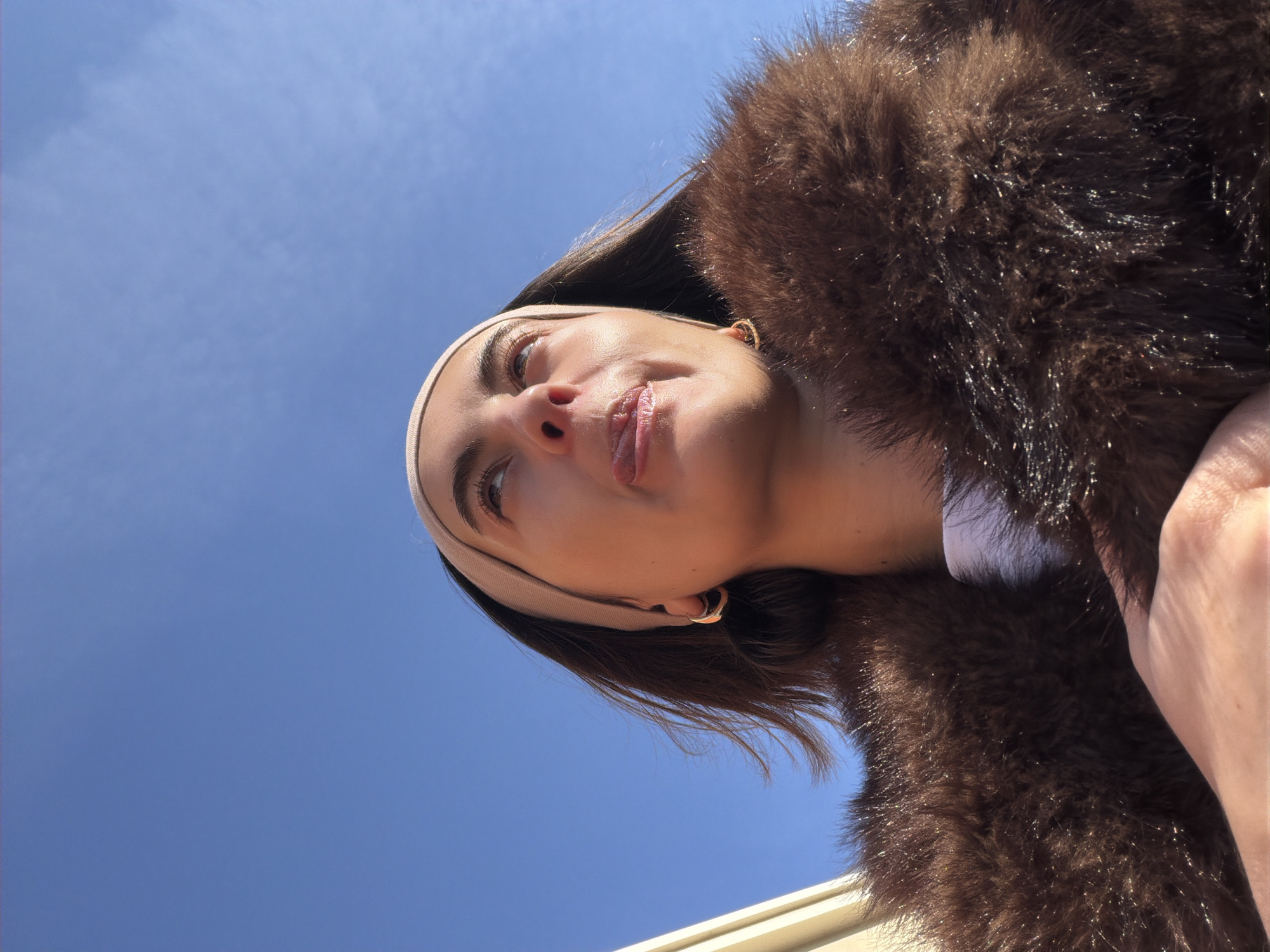 Woman in fur coat photographed against blue sky in Mascouche