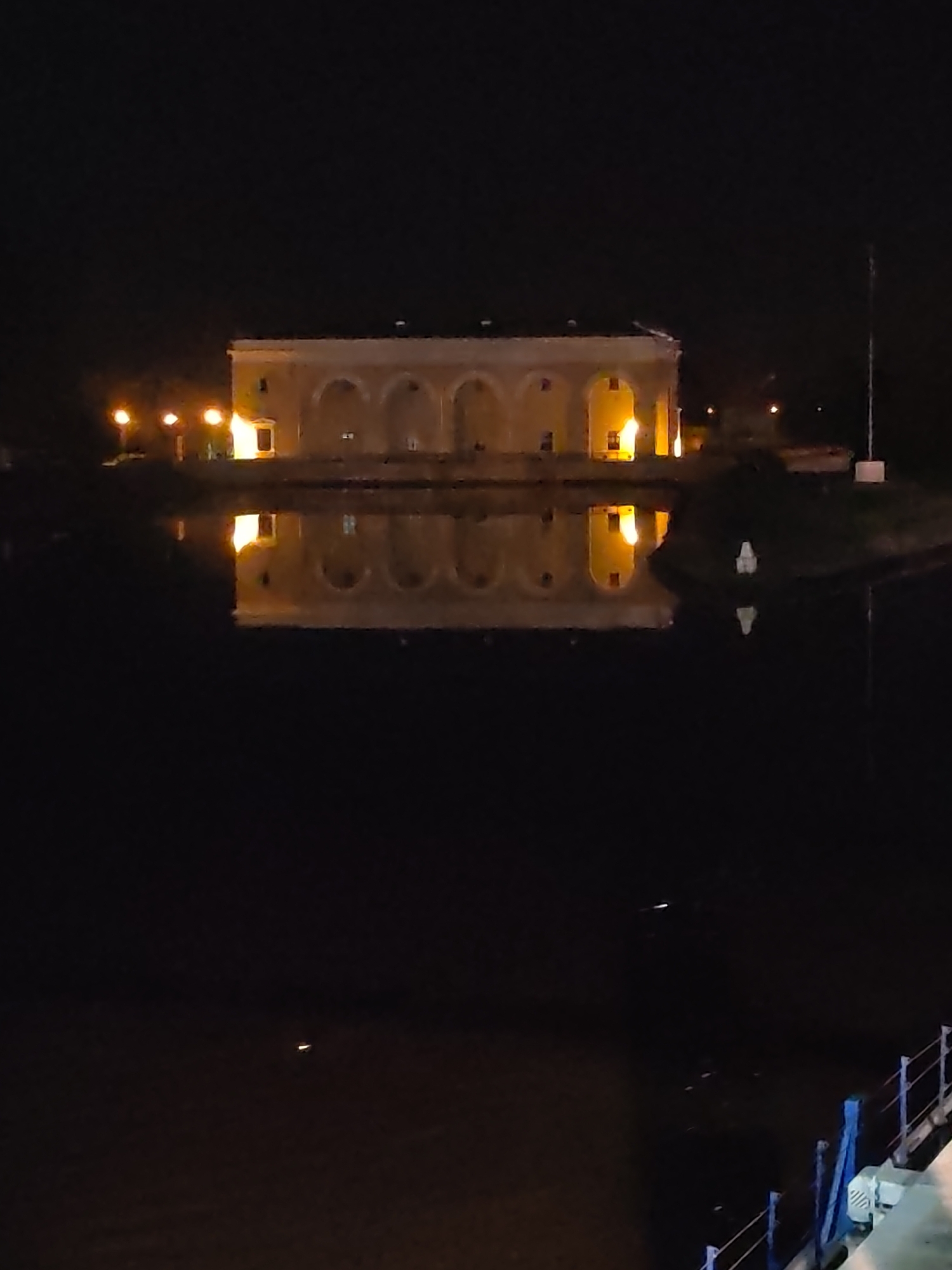 Illuminated building reflects in water at night in Dedenevo