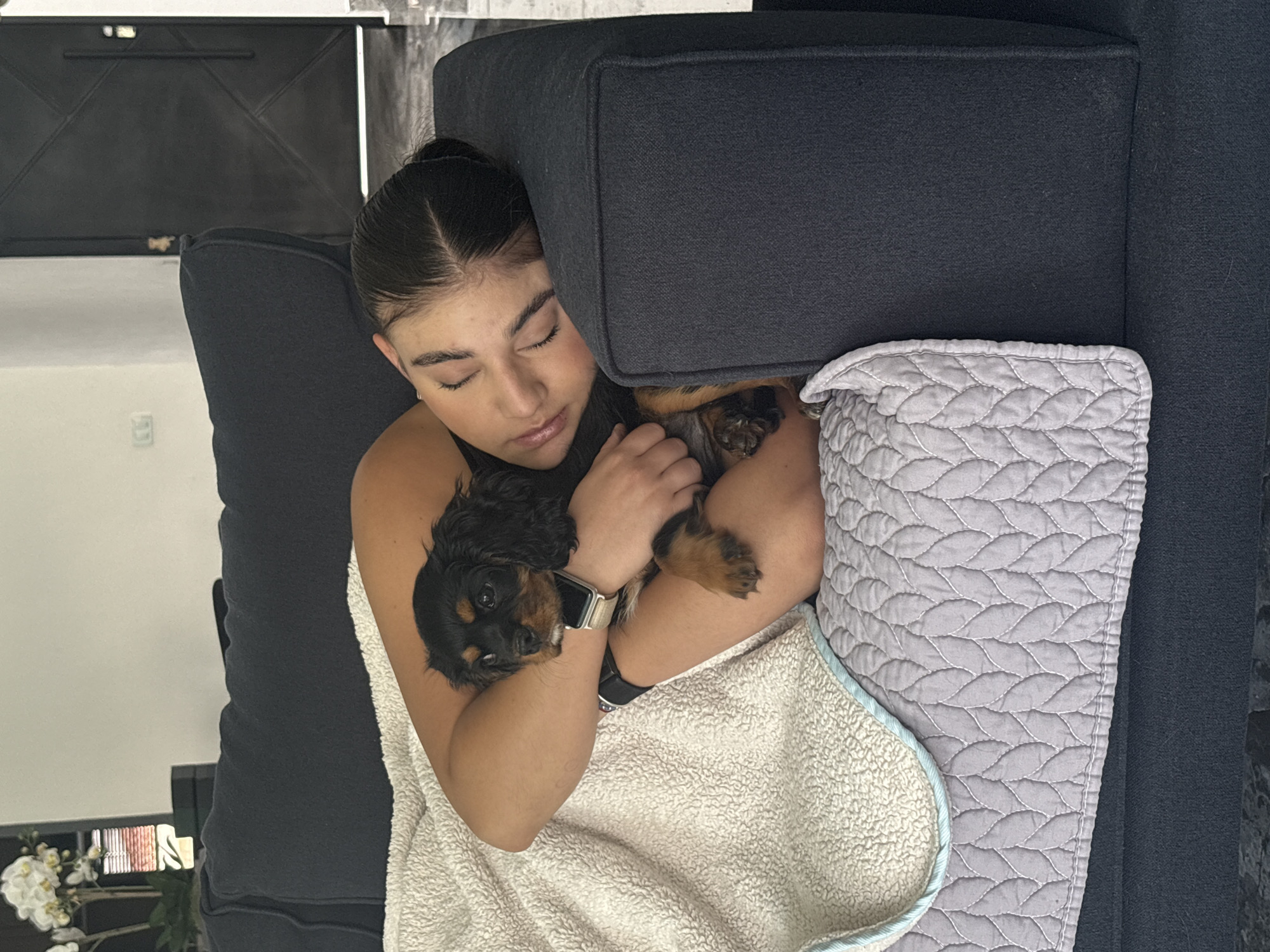 Woman naps with puppy on sofa in Puebla