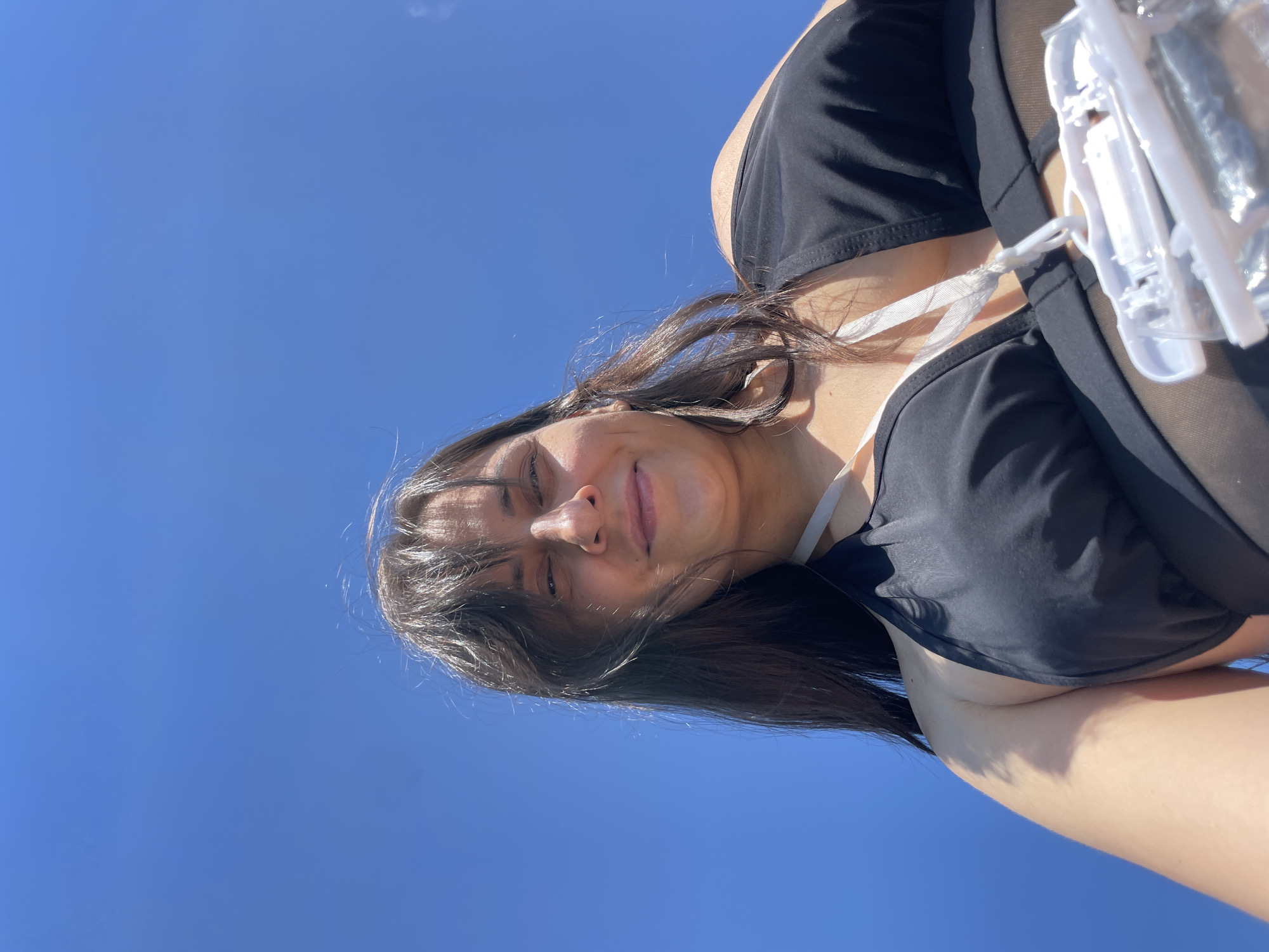 Low-angle poolside portrait against open blue sky