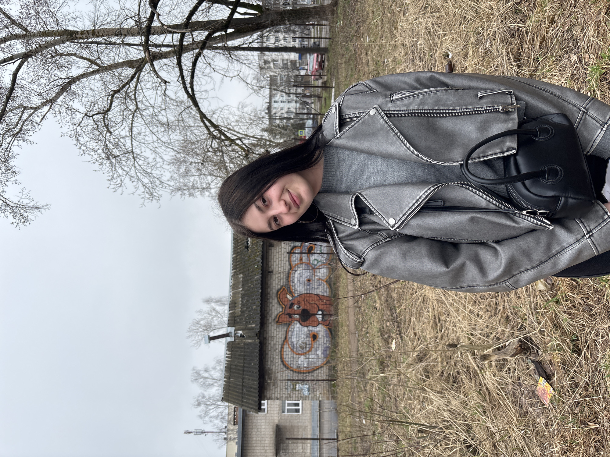 Woman photographed in casual portraits near graffitied building in Chaikovsky