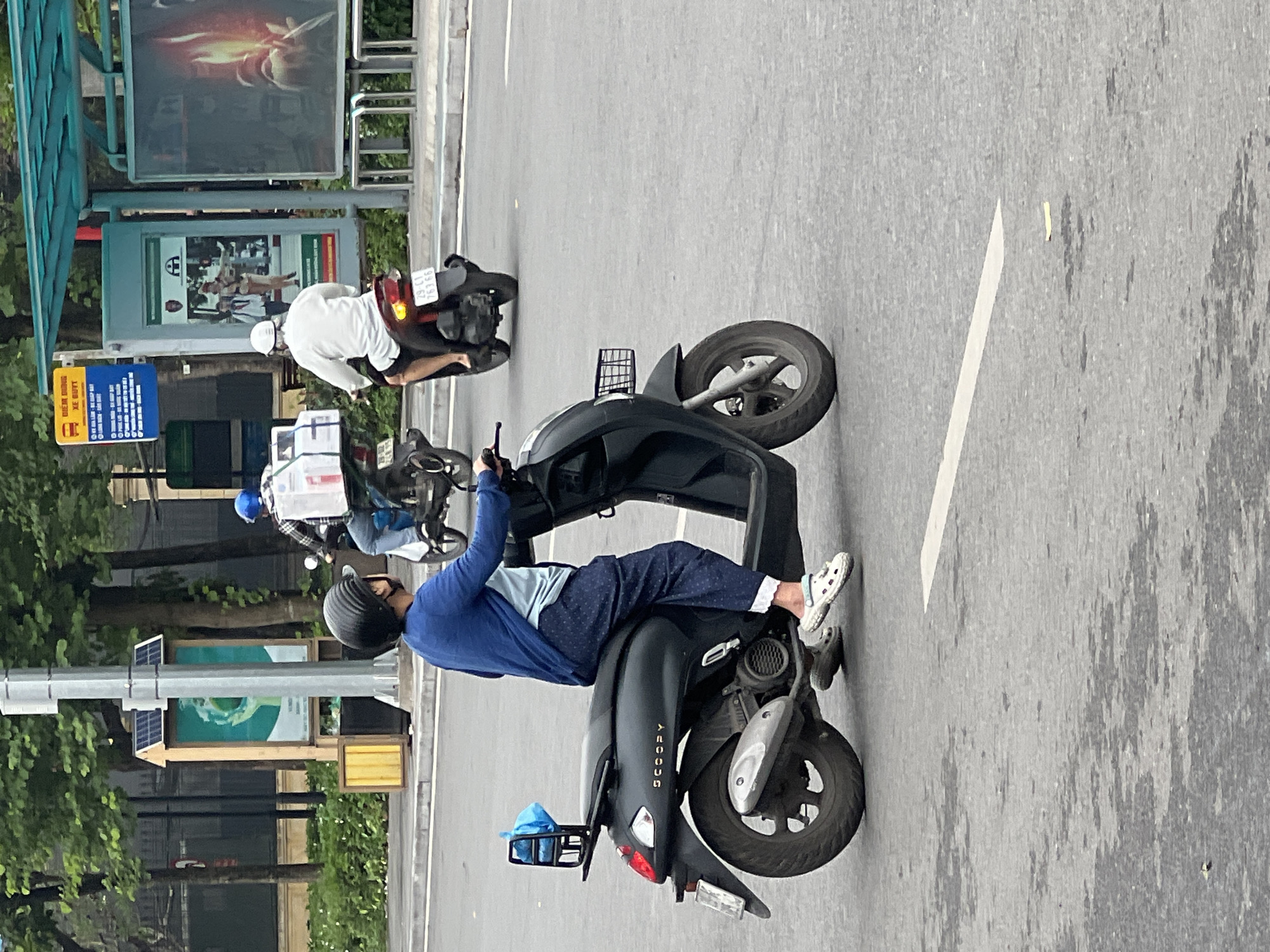 Wet morning scooter traffic on a Hanoi city street