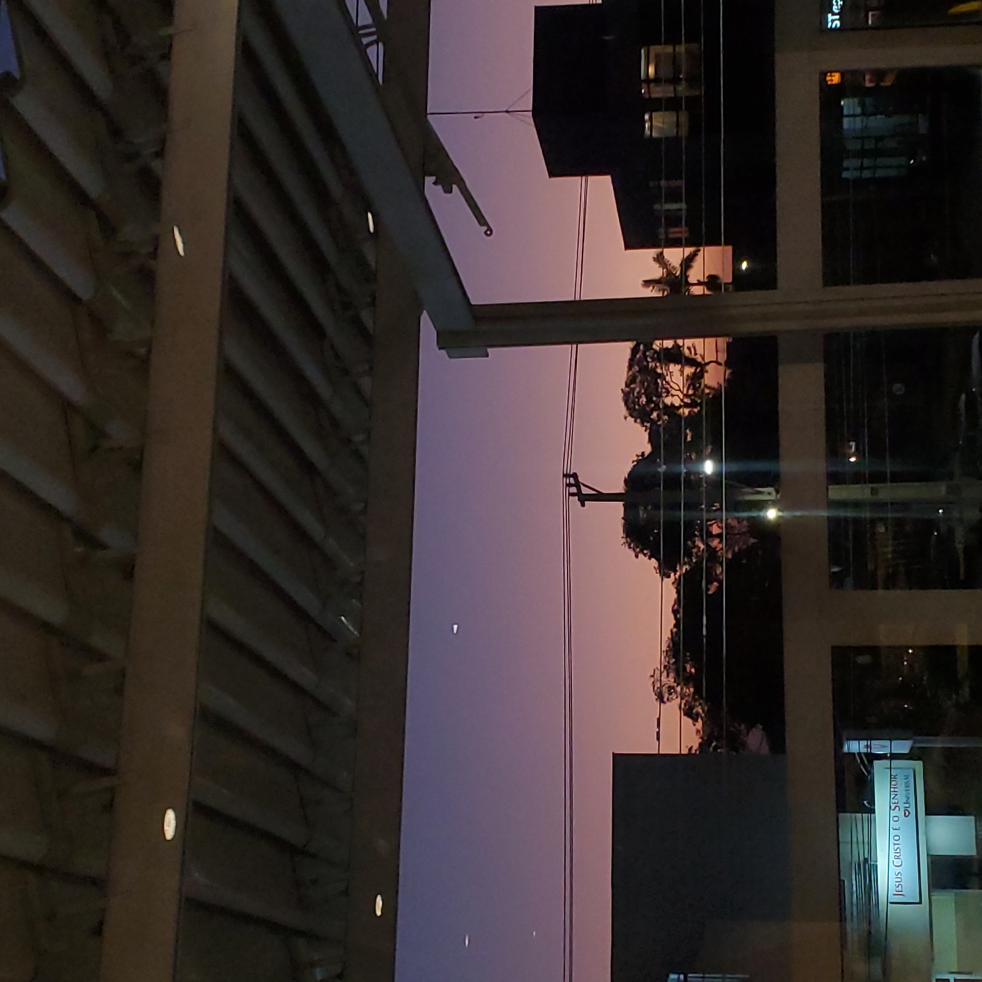 Evening cityscape photographed through metal framework in Curitiba
