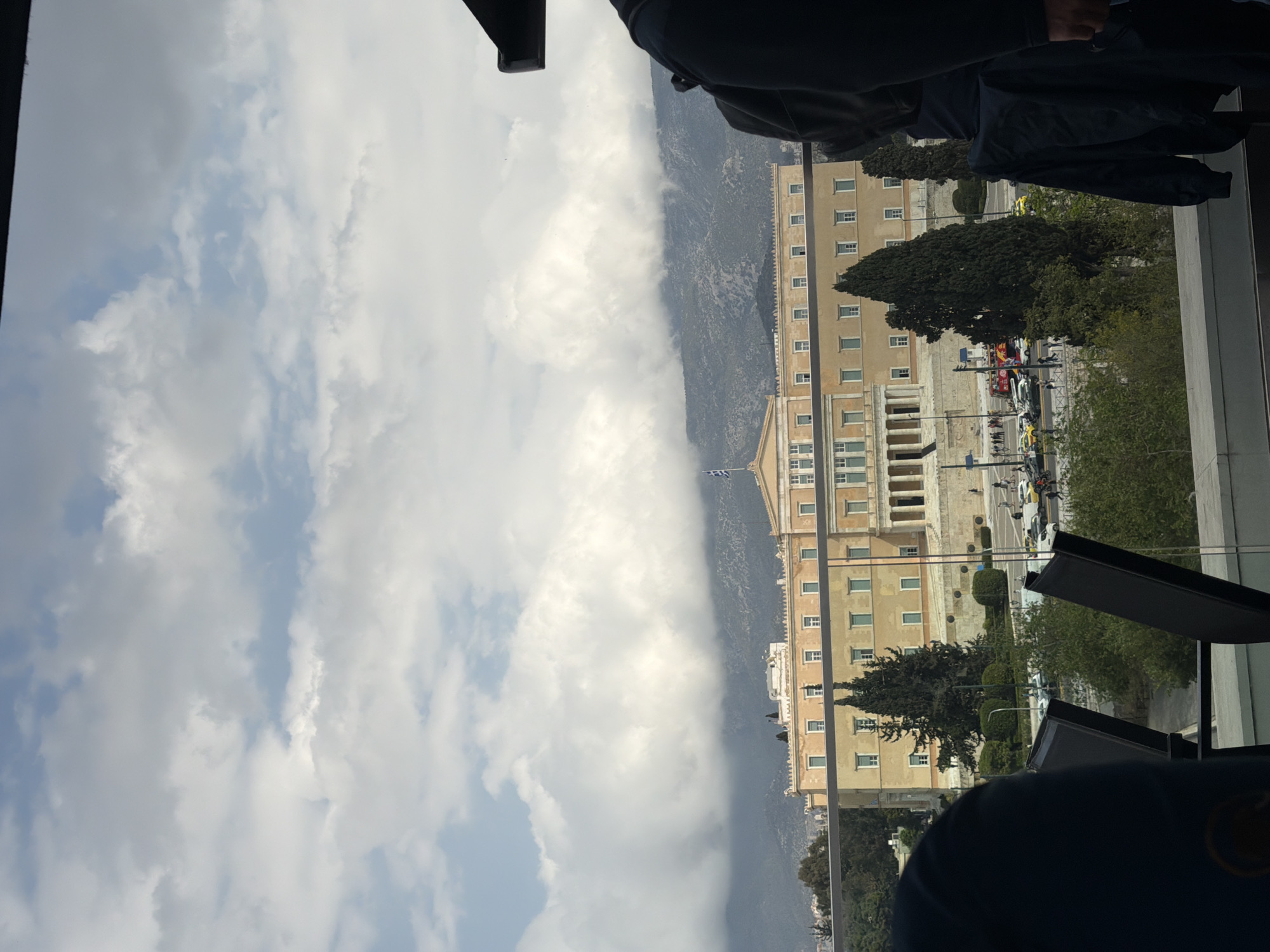 Woman takes selfies overlooking Athens Parliament from rooftop cafe