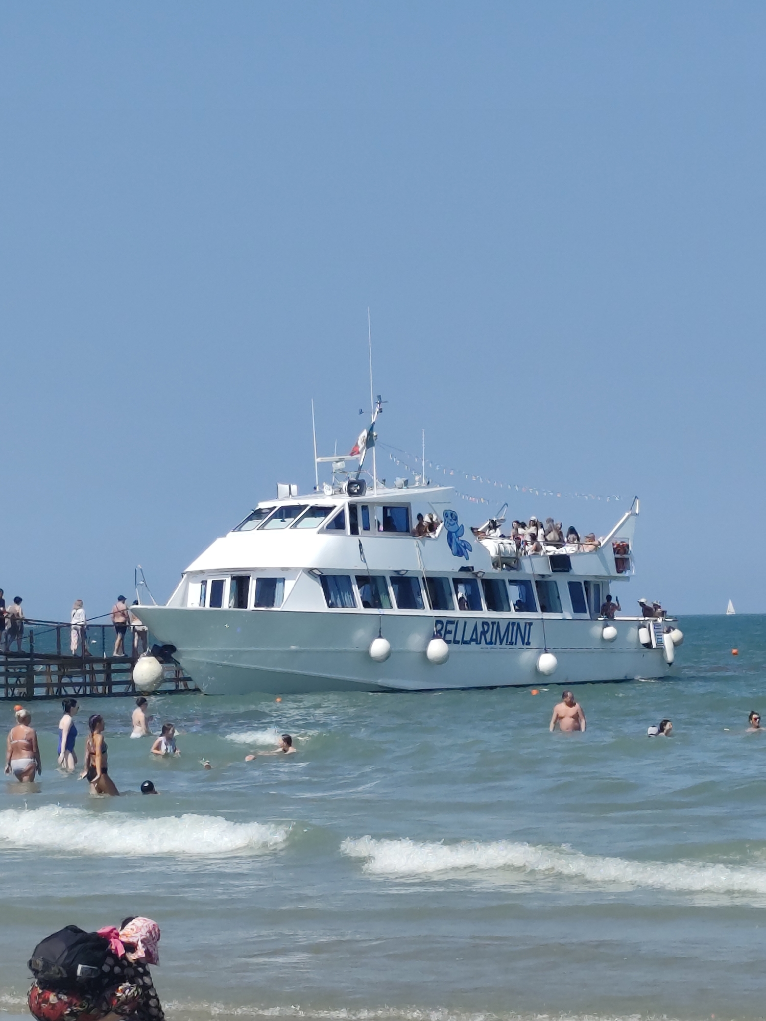 Kites, crowds, and a tourist boat on Rimini's summer beach
