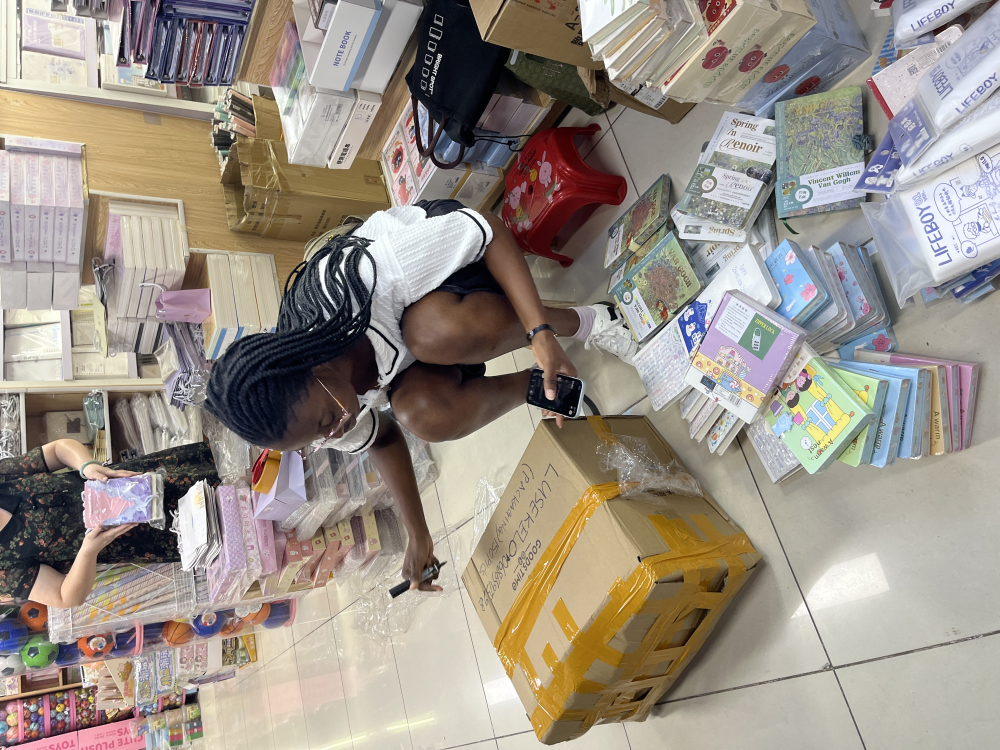 Inside a busy Liwan District stationery shop, customers and staff at work