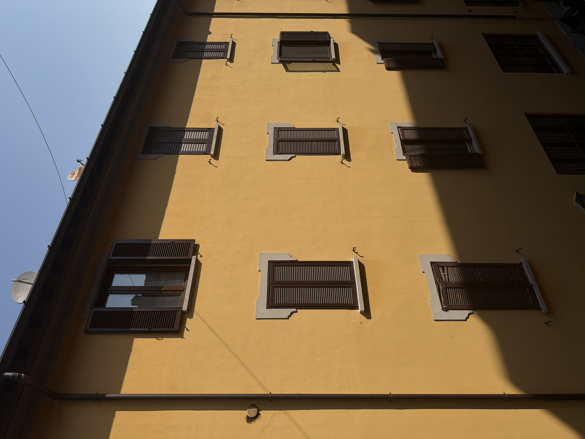 Yellow stucco building facade in Milan, tiled roof detail