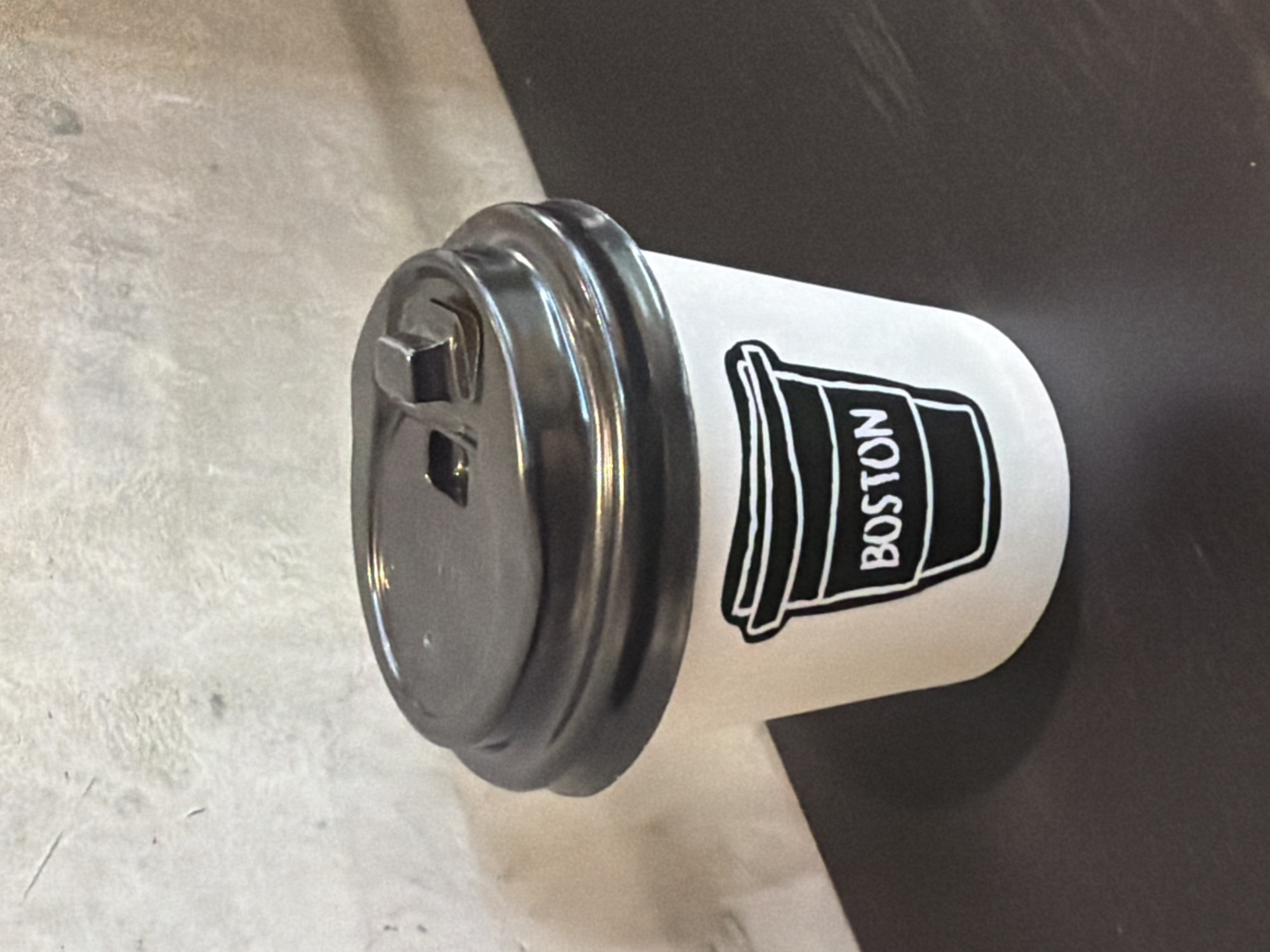 Boston-branded coffee cup observed lying horizontally on surface