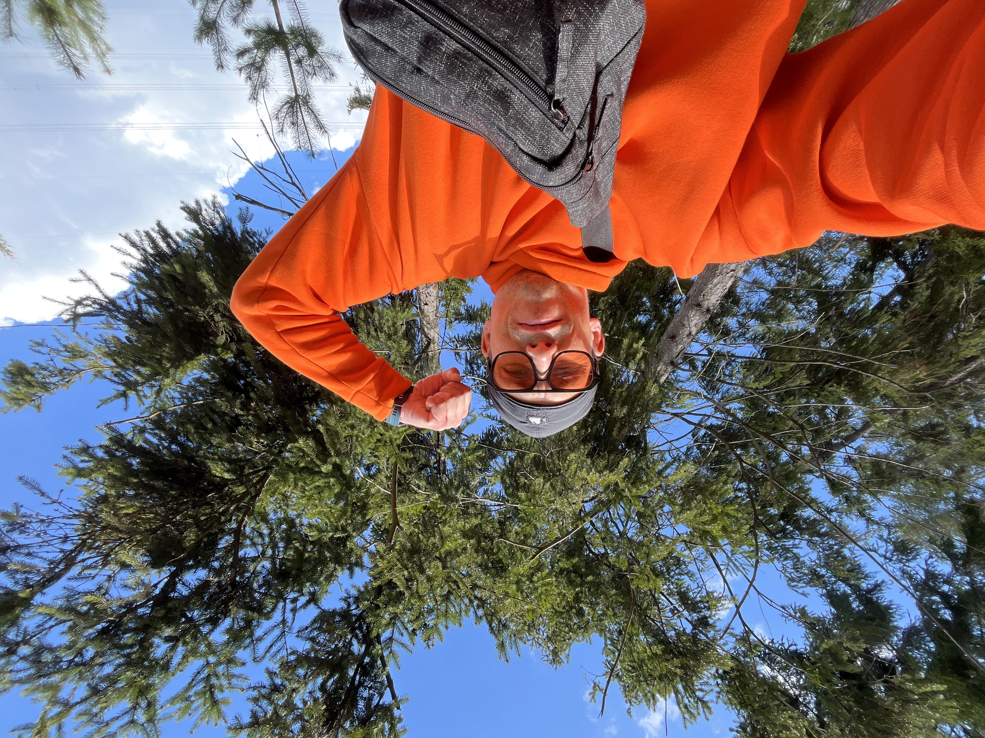 Person in orange outfit performs stunts, takes photos in Russian forest