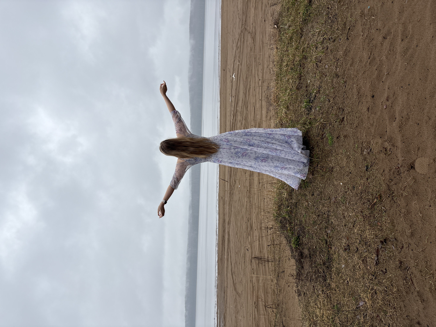 Woman stands on shoreline under cloudy skies in Chaikovsky