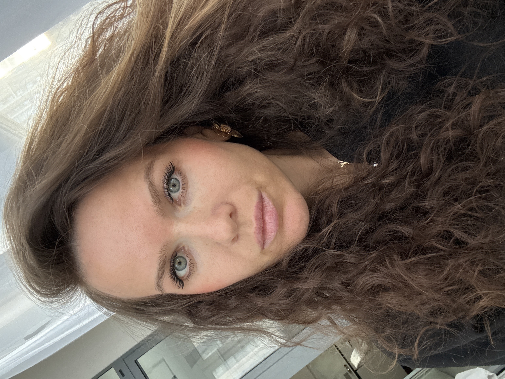 Woman with curly brown hair photographed in indoor workspace