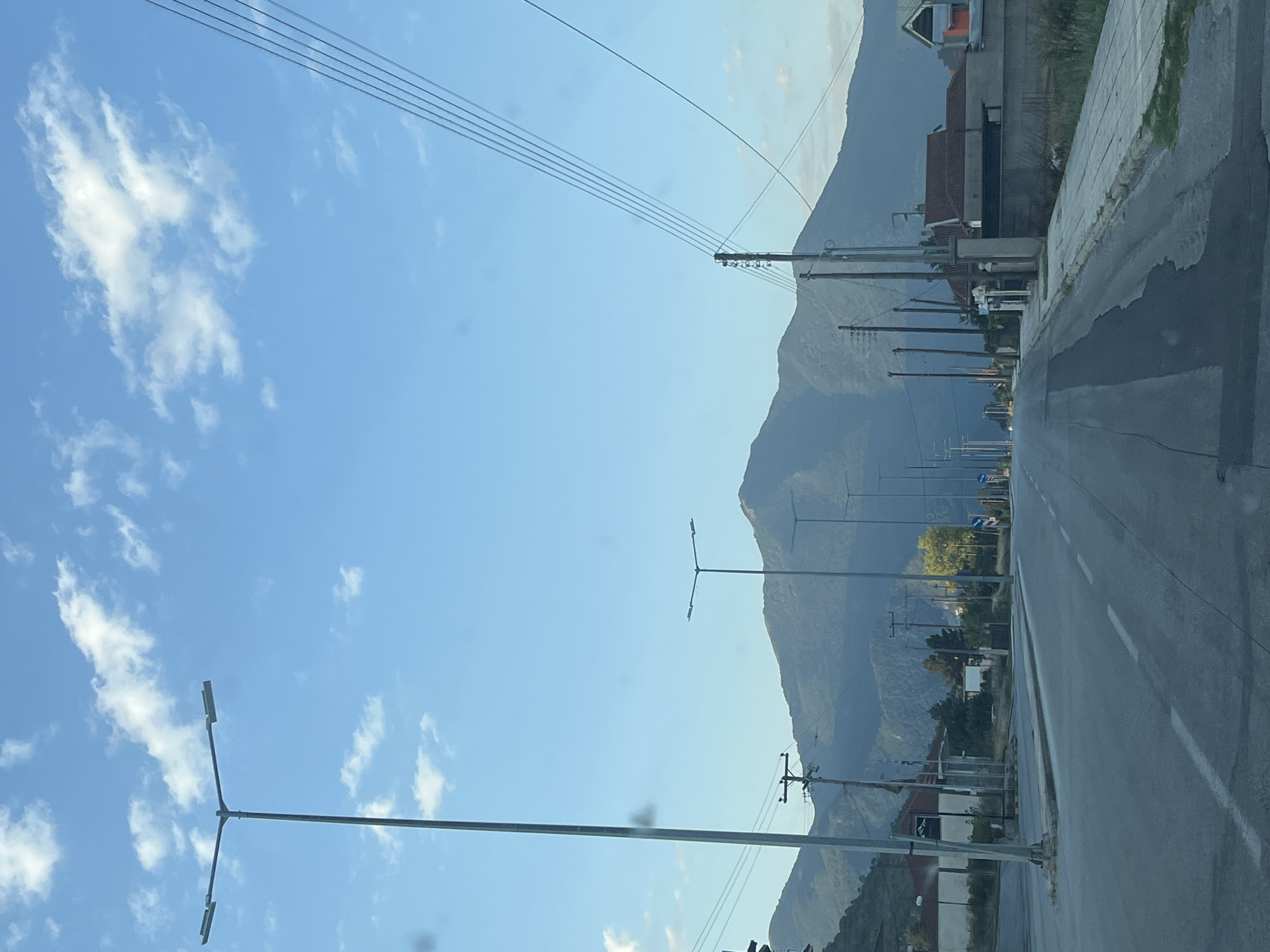 Tree-covered mountain backdrop frames a quiet Greek town road