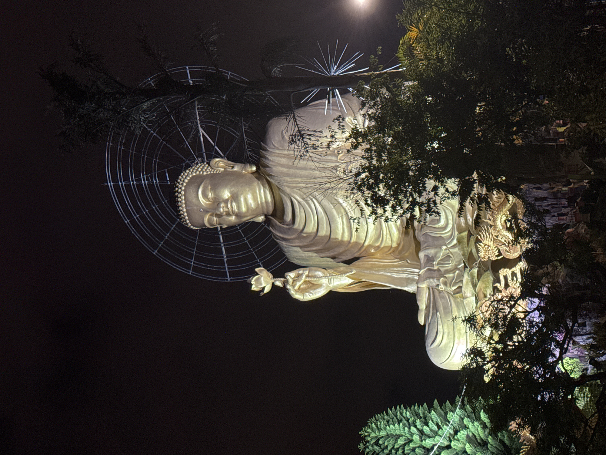 Golden Buddha statue illuminated at night in Đà Lạt