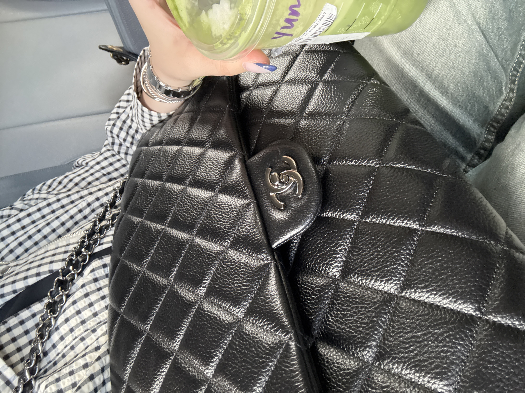 Person holds green drink over quilted bag in Chula Vista